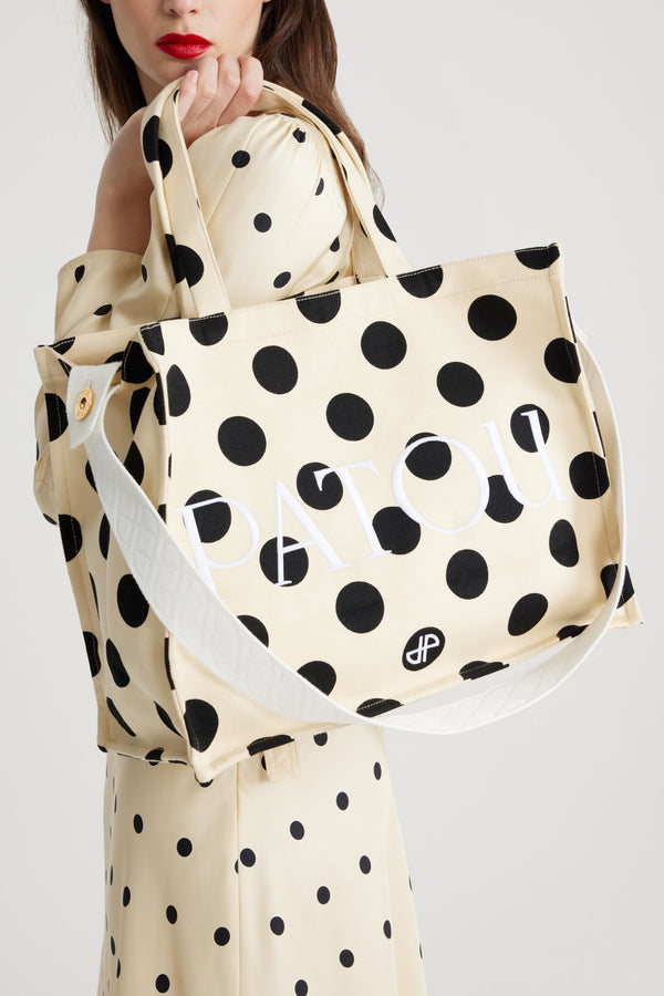 Patou - Grand cabas JP en coton imprimé - Angora Dots - Cabas en coton blanc cassé. Motif pois. Grand modèle. Patou et JP brodés. Bandoulière embossée avec détail de boutons dorés gravés Patou. Double anse. Peut se porter à la main ou sur l'épaule.