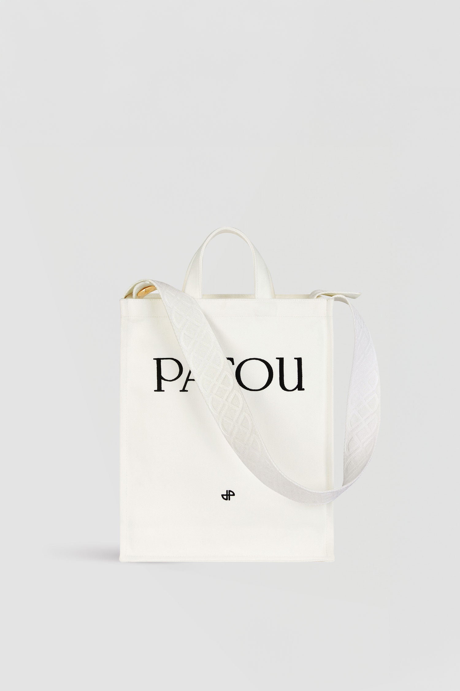 Patou - Cabas Patou vertical en coton - White - Un peu de Patou à emporter partout.Cabas en coton blanc. Patou et monogramme JP brodés. Bandoulière ornée de JP embossés avec détail de boutons dorés gravés Patou. Double anse. Peut se porter à la main ou sur l'épaule.