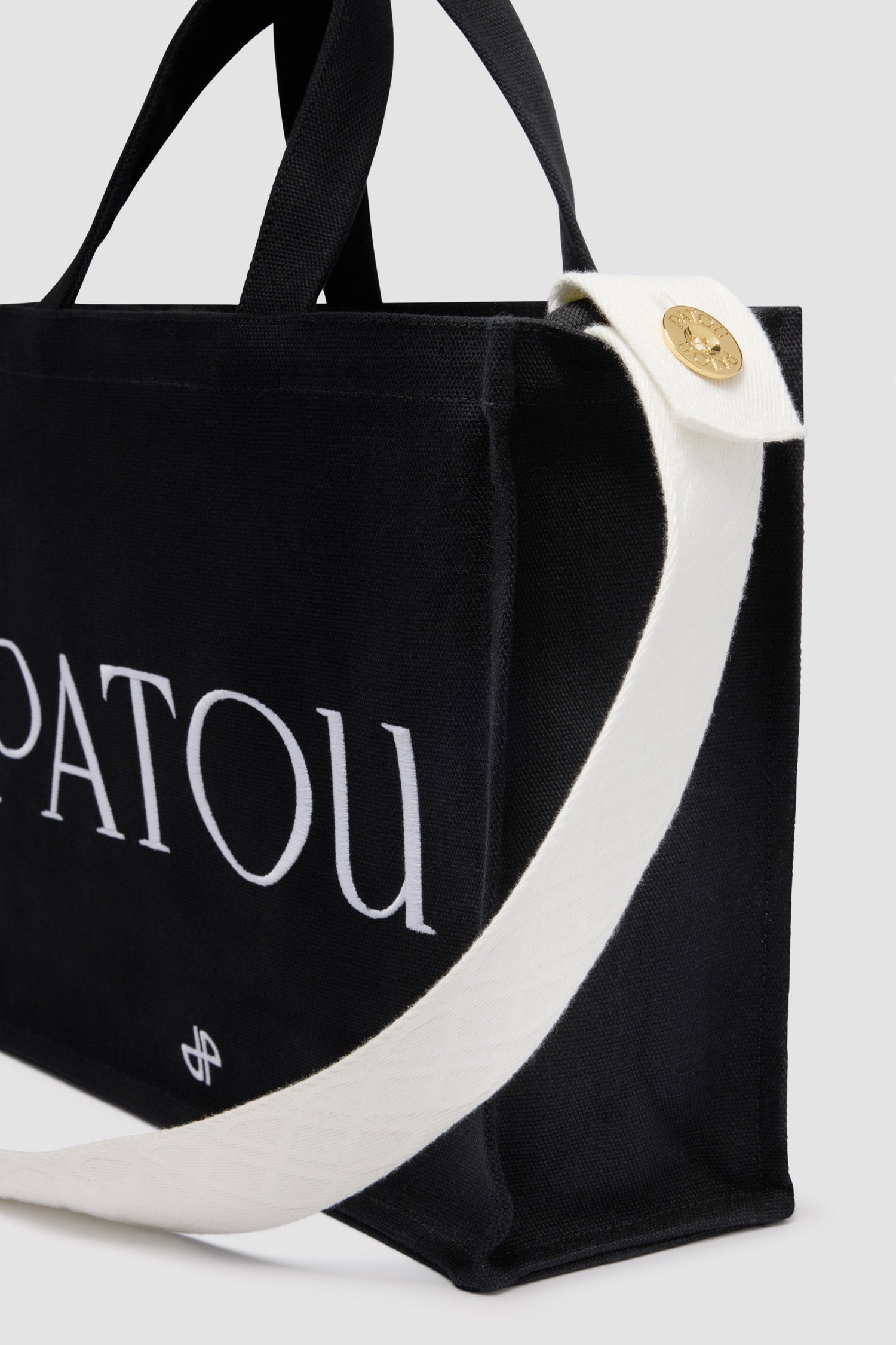 Patou - コットンキャンバス パトゥ ロゴトート ミディアム - Black - ブラックのコットンキャンバス製トート。ミディアムサイズのバージョン。パトゥの刺しゅうロゴとJPモノグラム。エンボス加工のショルダーストラップ、ゴールドトーンのパトゥロゴ刻印入りボタン。2つのトップハンドル。ハンドバックあるいはショルダーバックとしてご使用いただけます。