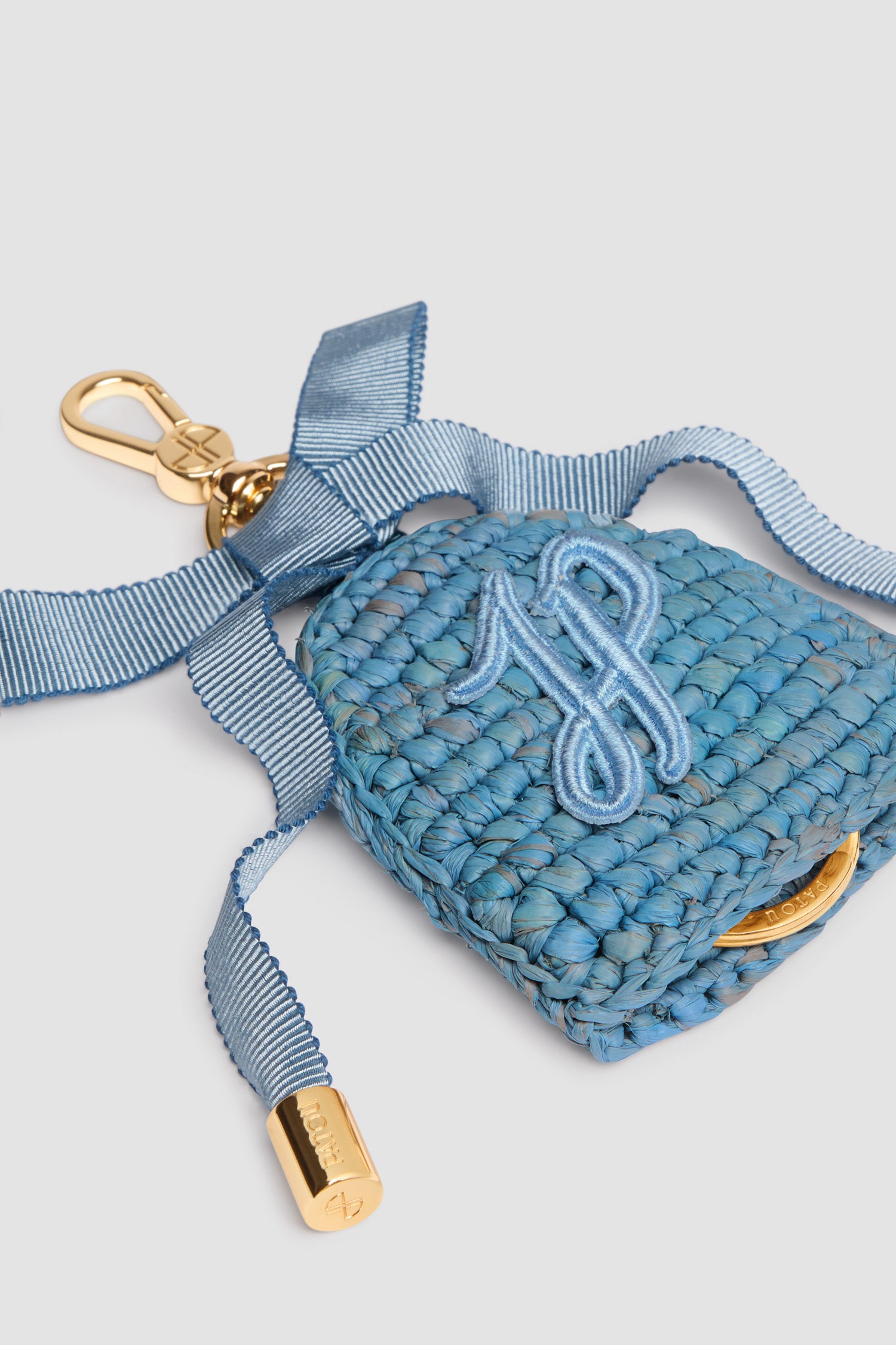 Patou - Schlüsselanhänger aus Raffiabast - Skylight Blue - Himmelblauer Schlüsselanhänger aus Raffiabast. Goldfarbener Hakenverschluss mit eingraviertem JP-Monogramm, befestigt an einer farblich passenden Schleife aus Grosgrain mit Metallspitzen. Farblich passende JP-Monogramm-Stickerei. Verdeckter Schlüsselring mit Patou Logogravur. Dieses Produkt wurde von Hand gefertigt.