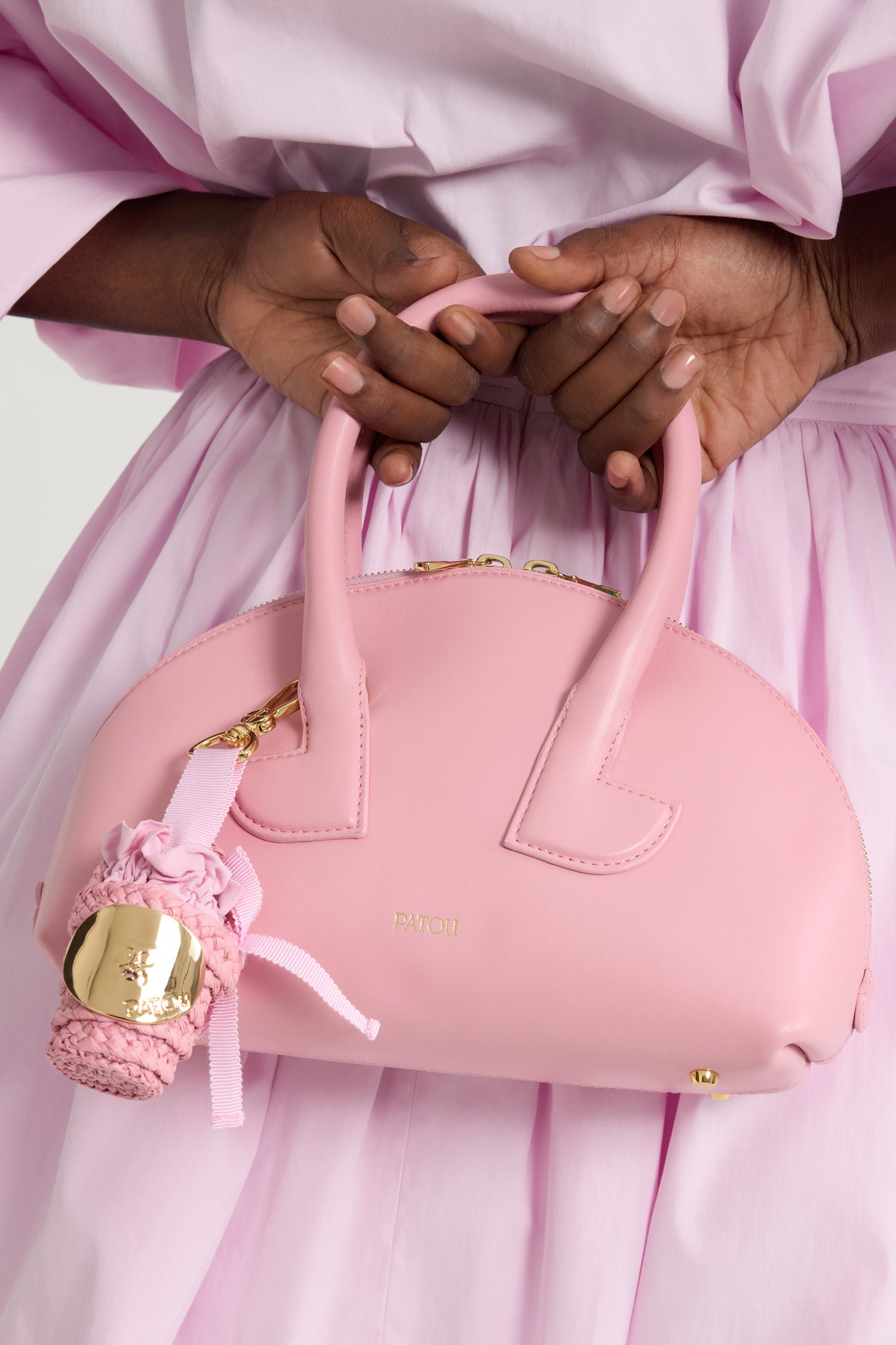 Patou - Iconic bucket charm in raffia - Primrose Pink - Primrose Pink raffia bucket charm. Gold-tone JP monogram-engraved hook fastening attached to a grosgrain bow with metal tips. Gold-tone embellishment inspired by the "Bocca della Verità" with engraved Patou logo. Tonal fabric lining with ruffle and bow.