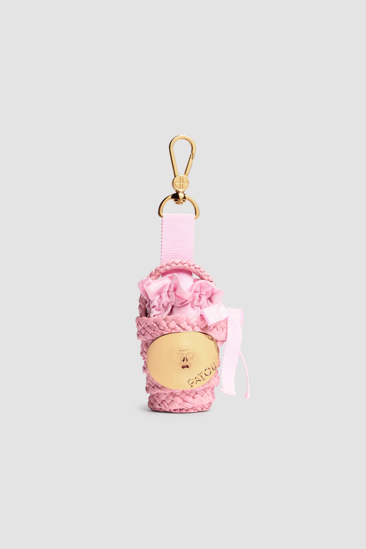 Patou - Iconic bucket charm in raffia - Primrose Pink - Primrose Pink raffia bucket charm. Gold-tone JP monogram-engraved hook fastening attached to a grosgrain bow with metal tips. Gold-tone embellishment inspired by the "Bocca della Verità" with engraved Patou logo. Tonal fabric lining with ruffle and bow.
