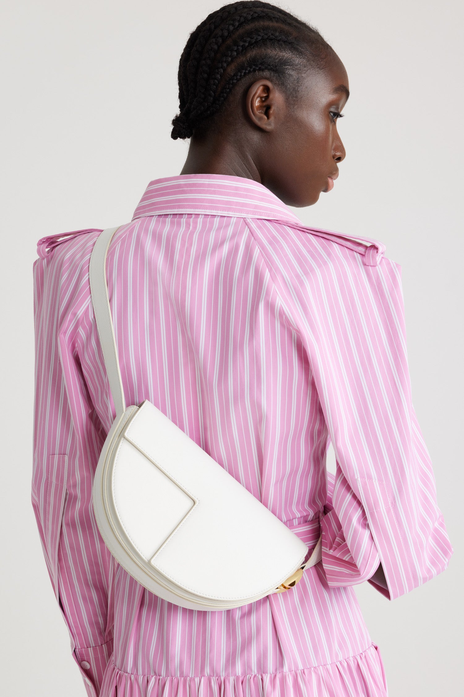 Patou - レザー製 Le Patou バッグ - Angora - アンゴラオフホワイトのレザー製ハンドバッグ。JPモノグラムにインスピレーションを得た幾何学的なカットアウトをあしらった半円形のフォルム。サイドにゴールドトーンのメタルパーツとJPモノグラム ディテール。調整可能なストラップで、ショルダーバッグ、クロスボディバッグ、ハンドバッグとしてお使いいただけます。ゴールドトーンのJPディテールをあしらったマグネットクロージャー。内部に複数のコンパートメント。エコライニング。長さ: 長さ: 25cm、高さ: 15cm、幅: 6cm ストラップの長さは3段階で調節可能:47 cm (ショルダー)、36 cm (クロスボディ)、28 cm (ハンド)