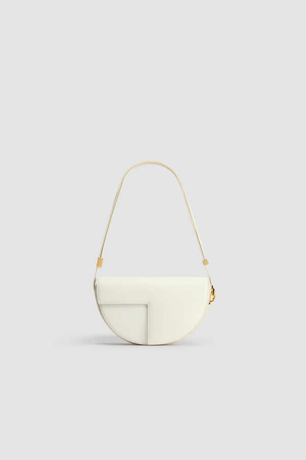 Patou - Le Patou bag in leather - Angora - Angora off-white leather handbag. Half-circle shape with geometric cut-outs inspired by the JP monogram. Gold-tone hardware with JP monogram detail at the side. Adjustable strap that allows it to be worn on the shoulder, across the body or carried by hand. Magnetic closure with gold-tone JP detail. Multiple compartments inside. Eco lining.Measures: 25 cm (length), 15 cm (height), 6 cm (depth)3 lengths for the adjustable strap: 47 cm (on the shoulder), 36 cm (across the body), 28 cm (carried by hand)