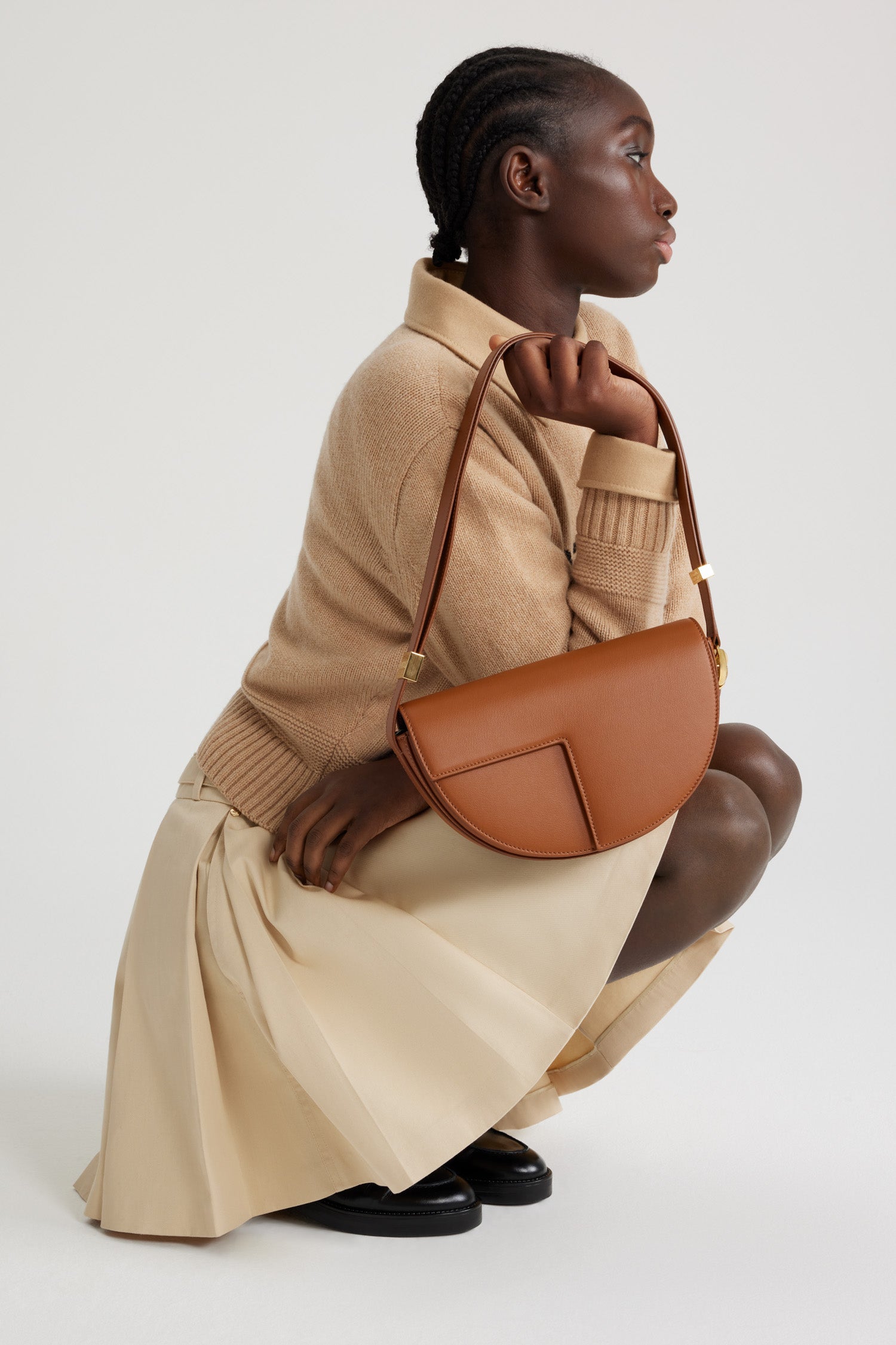 Patou - レザー製 Le Patou バッグ - Autumn Leaf - オータムリーフブラウンのレザー製ハンドバッグ。未使用の高品質皮革を用いた独自素材を使用。番号入り60点限定エディション。JPモノグラムにインスピレーションを得た幾何学的なカットアウトをあしらった半円形のフォルム。サイドにゴールドトーンのメタルパーツとJPモノグラム ディテール。調整可能なストラップで、ショルダーバッグ、クロスボディバッグ、ハンドバッグとしてお使いいただけます。ゴールドトーンのJPディテールをあしらったマグネットクロージャー。内部に複数のコンパートメント。エコライニング。長さ: 長さ: 25cm、高さ: 15cm、幅: 6cm ストラップの長さは3段階で調節可能:47 cm (ショルダー)、36 cm (クロスボディ)、28 cm (ハンド)