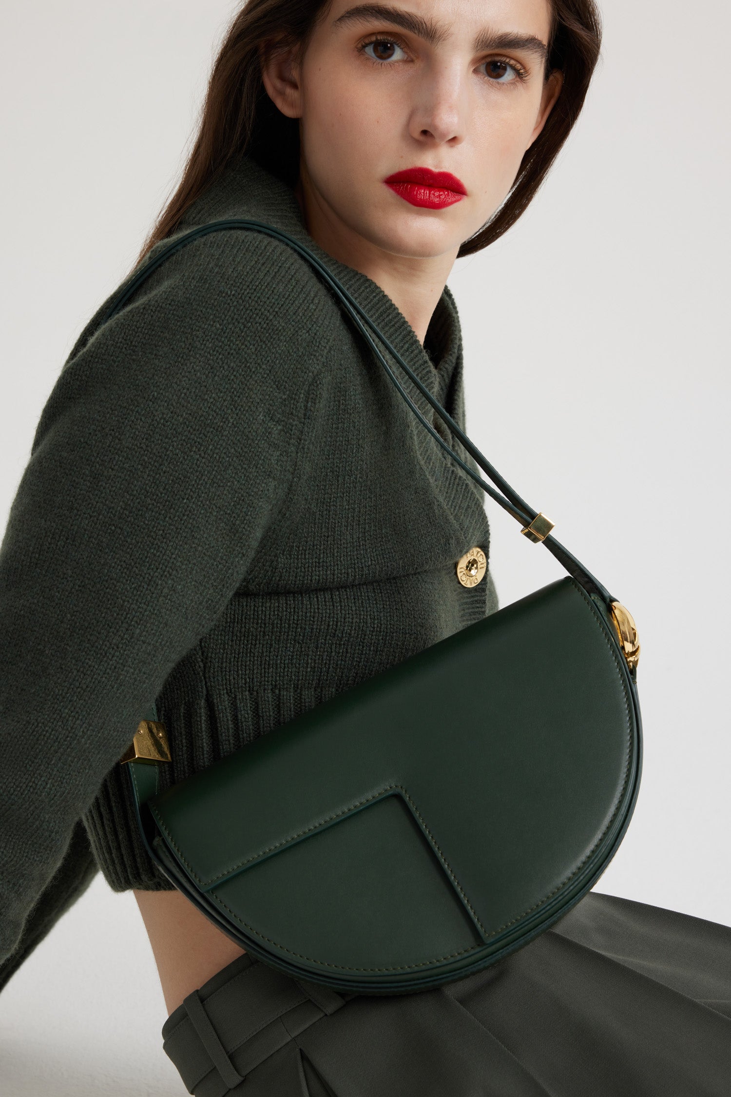 Patou - Le Patou - Bottle Green - Sac en cuir vert bouteille. Forme demi-lune avec découpes géométriques inspirée du monogramme JP. Pièces en métal doré avec détail JP inspiré d'une broche des archives Jean Patou. Bandoulière ajustable permettant un porté épaule, en bandoulière ou à la main. Fermeture aimantée avec détail JP doré. Compartiments multiples à l'intérieur.Dimensions : 25 cm de longueur, 15 cm de hauteur et 6 cm de profondeurBandoulière ajustable en 3 longueurs : 47 cm (sur l'épaule), 36 cm (en bandoulière), 28 cm (porté à la main)