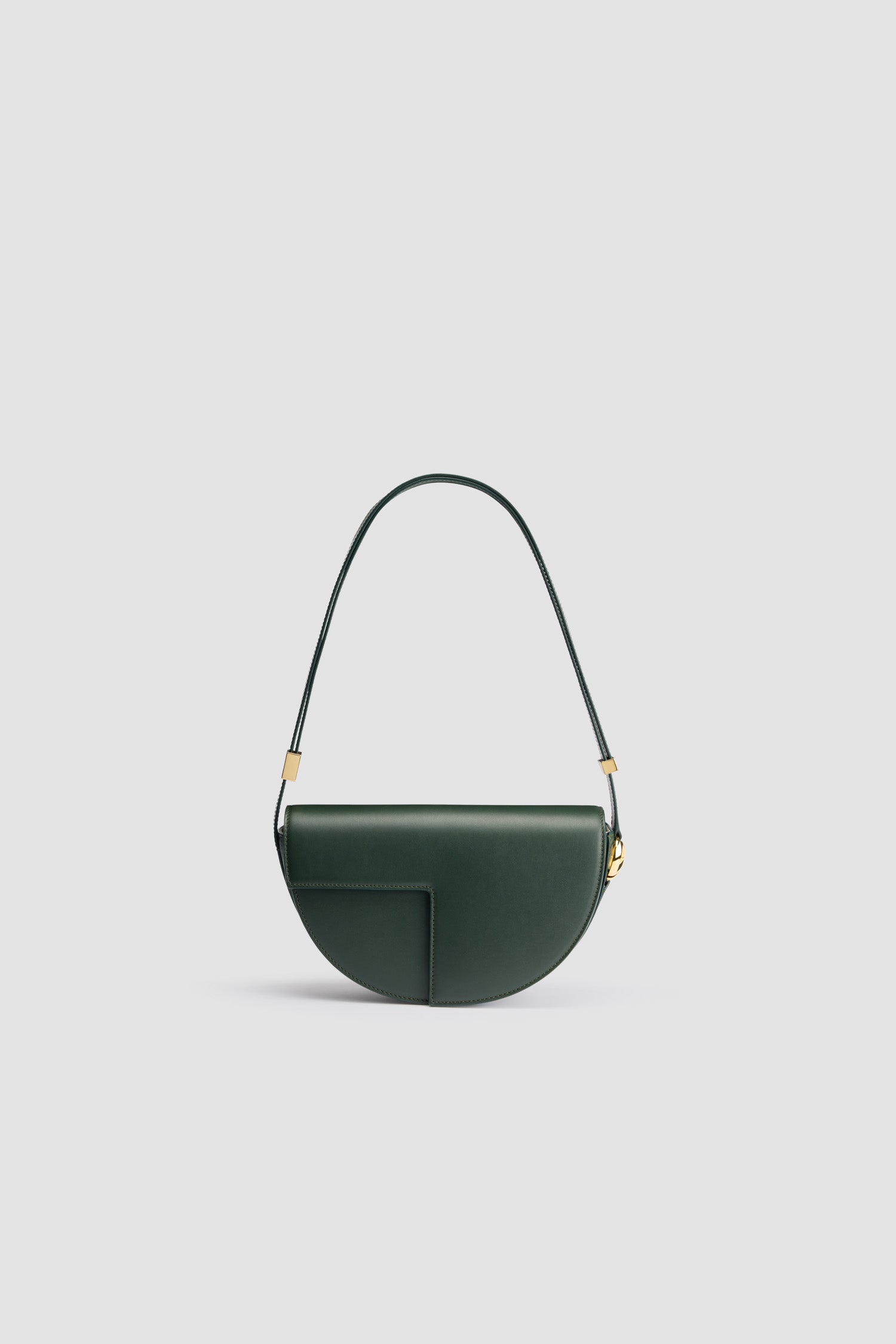 Patou - Le Patou - Bottle Green - Sac en cuir vert bouteille. Forme demi-lune avec découpes géométriques inspirée du monogramme JP. Pièces en métal doré avec détail JP inspiré d'une broche des archives Jean Patou. Bandoulière ajustable permettant un porté épaule, en bandoulière ou à la main. Fermeture aimantée avec détail JP doré. Compartiments multiples à l'intérieur.Dimensions : 25 cm de longueur, 15 cm de hauteur et 6 cm de profondeurBandoulière ajustable en 3 longueurs : 47 cm (sur l'épaule), 36 cm (en bandoulière), 28 cm (porté à la main)