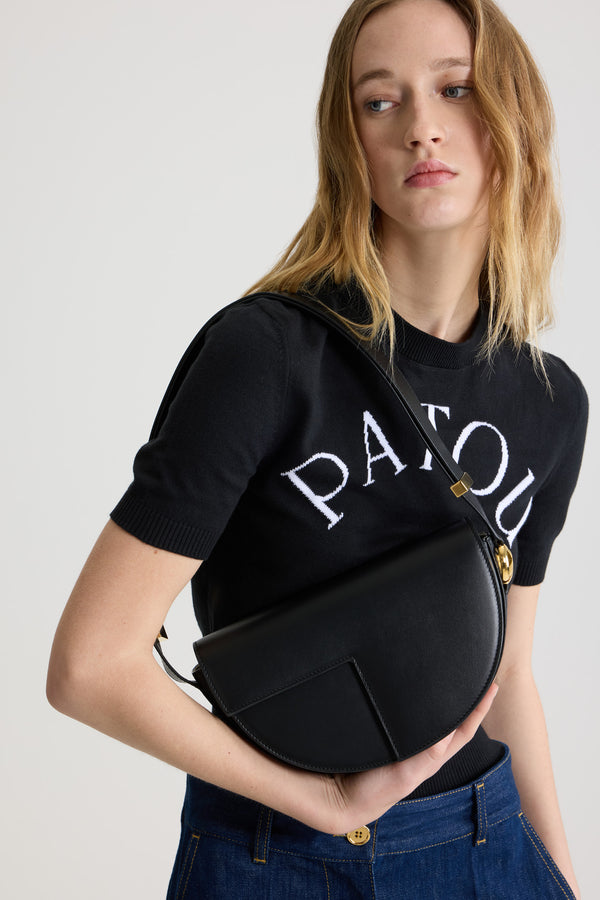Patou - Le Patou bag in leather - Black - Black smooth leather handbag. Half-circle shape with geometric cut-outs inspired by the JP monogram. Gold-tone hardware with JP monogram detail at the side. Adjustable strap that allows it to be worn on the shoulder, across the body or carried by hand. Magnetic closure with gold-tone JP detail. Multiple compartments inside.Measures: 25 cm (length), 15 cm (height), 6 cm (depth)3 lengths for the adjustable strap: 47 cm (on the shoulder), 36 cm (across the body), 28 cm (carried by hand)