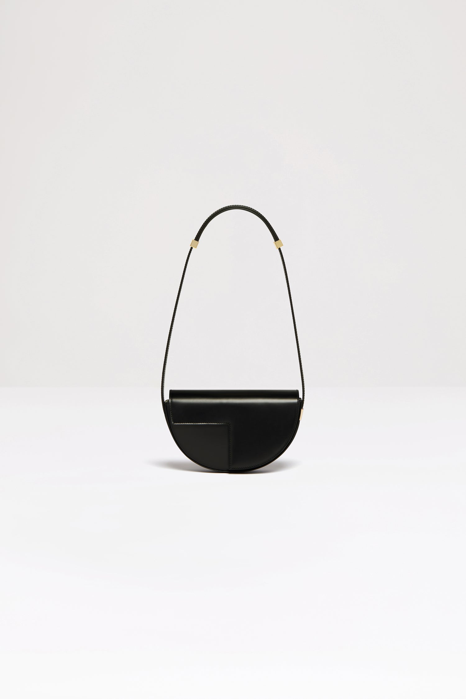 Patou - Le Petit Patou bag in leather - Black - A smaller take on everyone's favourite piece of Patou!Black leather handbag. Crafted using unique materials sourced from unused high-quality leather hides. 80 limited numbered edition. Half-circle shape with geometric cut-outs inspired by the JP monogram. Gold-tone hardware with Patou-engraved detail at the side. Adjustable strap that allows it to be worn on the shoulder, across the body or carried by hand. Magnetic closure with gold-tone JP detail. Internal compartment. Eco lining.Measures: 20cm (length), 13cm (height), 5cm (depth)