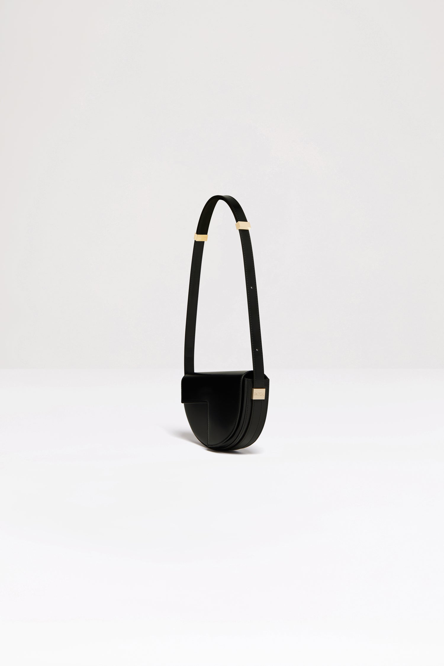 Patou - Le Petit Patou bag in leather - Black - A smaller take on everyone's favourite piece of Patou!Black leather handbag. Crafted using unique materials sourced from unused high-quality leather hides. 80 limited numbered edition. Half-circle shape with geometric cut-outs inspired by the JP monogram. Gold-tone hardware with Patou-engraved detail at the side. Adjustable strap that allows it to be worn on the shoulder, across the body or carried by hand. Magnetic closure with gold-tone JP detail. Internal compartment. Eco lining.Measures: 20cm (length), 13cm (height), 5cm (depth)