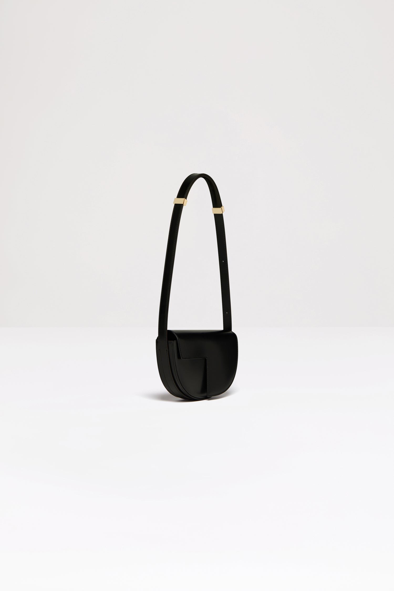 Patou - Le Petit Patou bag in leather - Black - A smaller take on everyone's favourite piece of Patou!Black leather handbag. Crafted using unique materials sourced from unused high-quality leather hides. 80 limited numbered edition. Half-circle shape with geometric cut-outs inspired by the JP monogram. Gold-tone hardware with Patou-engraved detail at the side. Adjustable strap that allows it to be worn on the shoulder, across the body or carried by hand. Magnetic closure with gold-tone JP detail. Internal compartment. Eco lining.Measures: 20cm (length), 13cm (height), 5cm (depth)