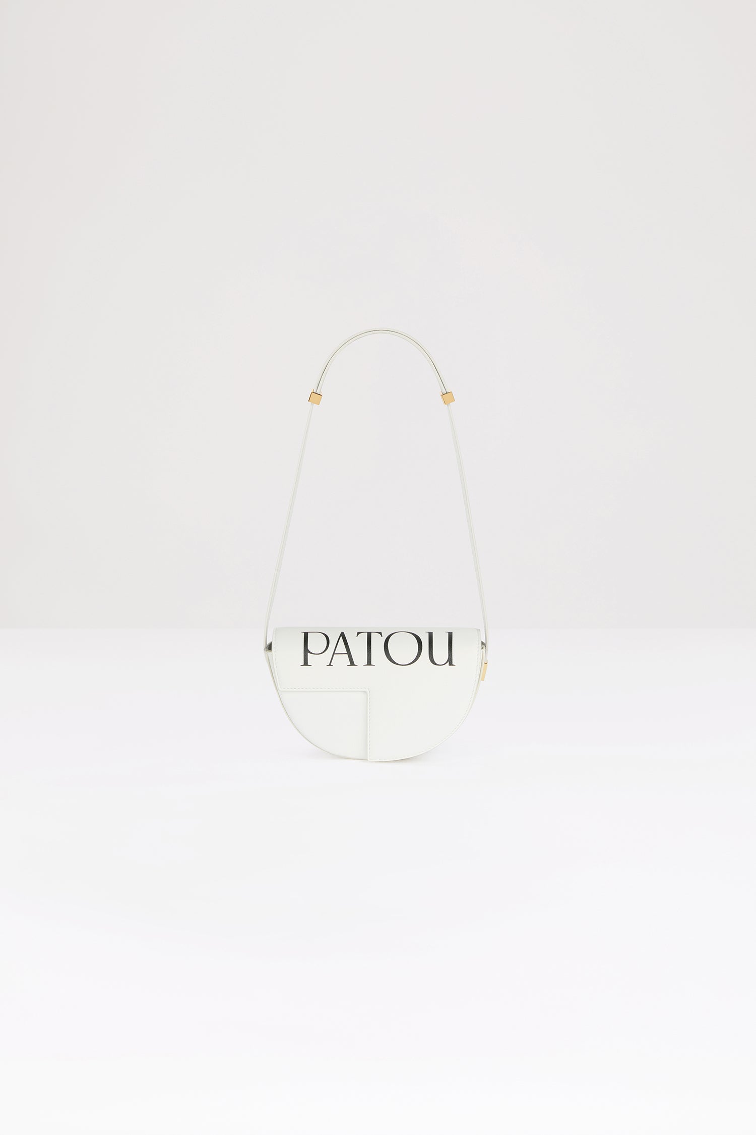 Patou - 로고 장식 르 쁘띠 파투 가죽 백 - White Black Logo - 작은 사이즈로 제작된 파투의 시그니처 파투 백.화이트 컬러의 가죽 소재. 상단의 Patou 프린트. 100점 한정 생산 리미티드 에디션. JP 모노그램에서 영감을 받은 기하학적 컷아웃이 돋보이는 반원형 실루엣. 측면의 Patou가 새겨진 골드 톤 하드웨어. 길이 조절 가능한 스트랩으로 숄더백, 크로스백, 또는 토트백 스타일로 연출 가능. 골드 톤 JP 디테일의 자석 잠금. 내부 수납공간. 에코 내부 마감.사이즈: 20cm(길이), 13cm(높이), 5cm(깊이)
