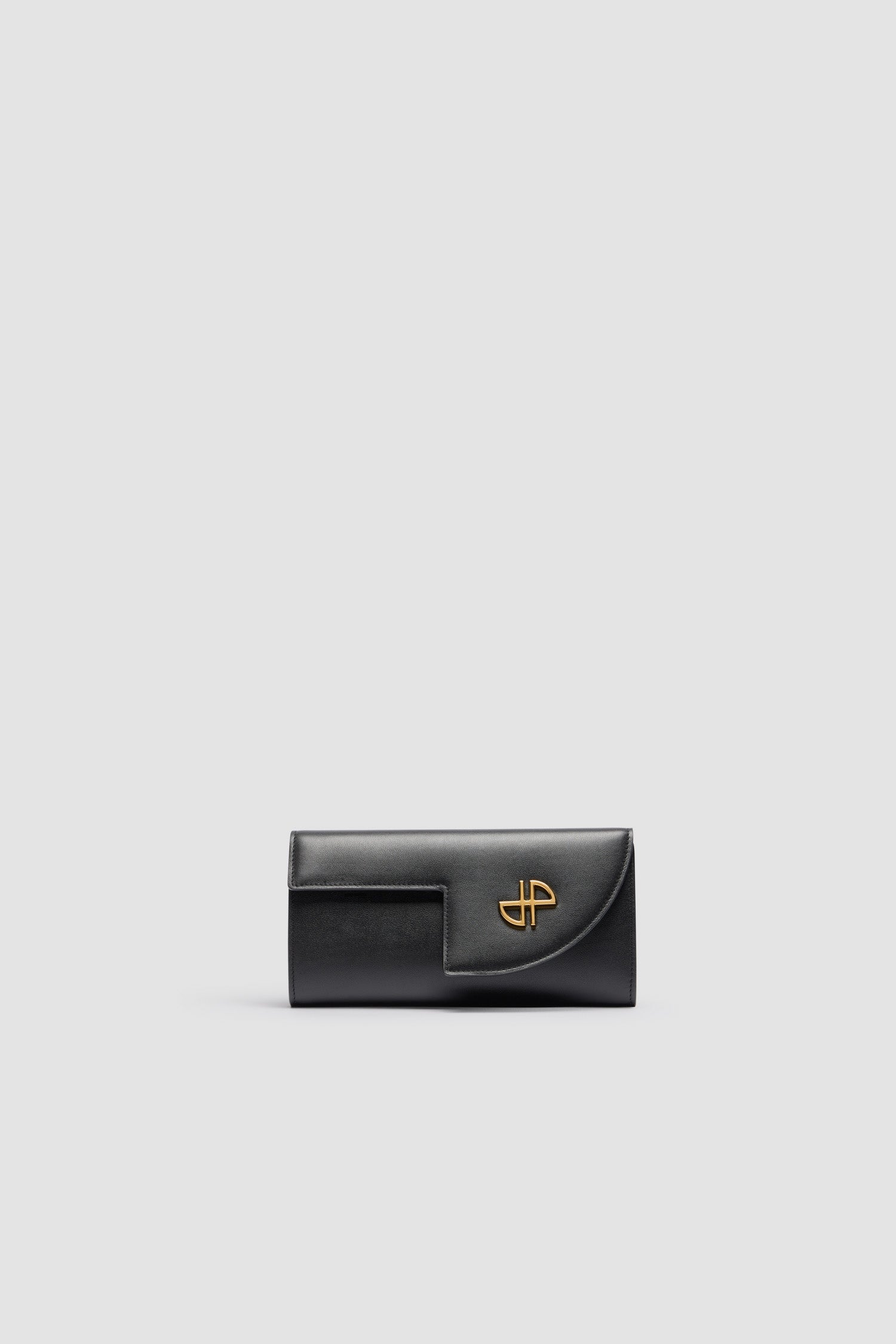 Patou - JP chain clutch in leather - Black - A party bag with a Patou soul.Black leather clutch. Crafted using unique materials sourced from unused high-quality leather hides. Compact design. Gold-tone chain strap. Cut-out flap with gold-tone JP embellishment. Snap closure. Zipped compartment. Gold embossed Patou at the back.