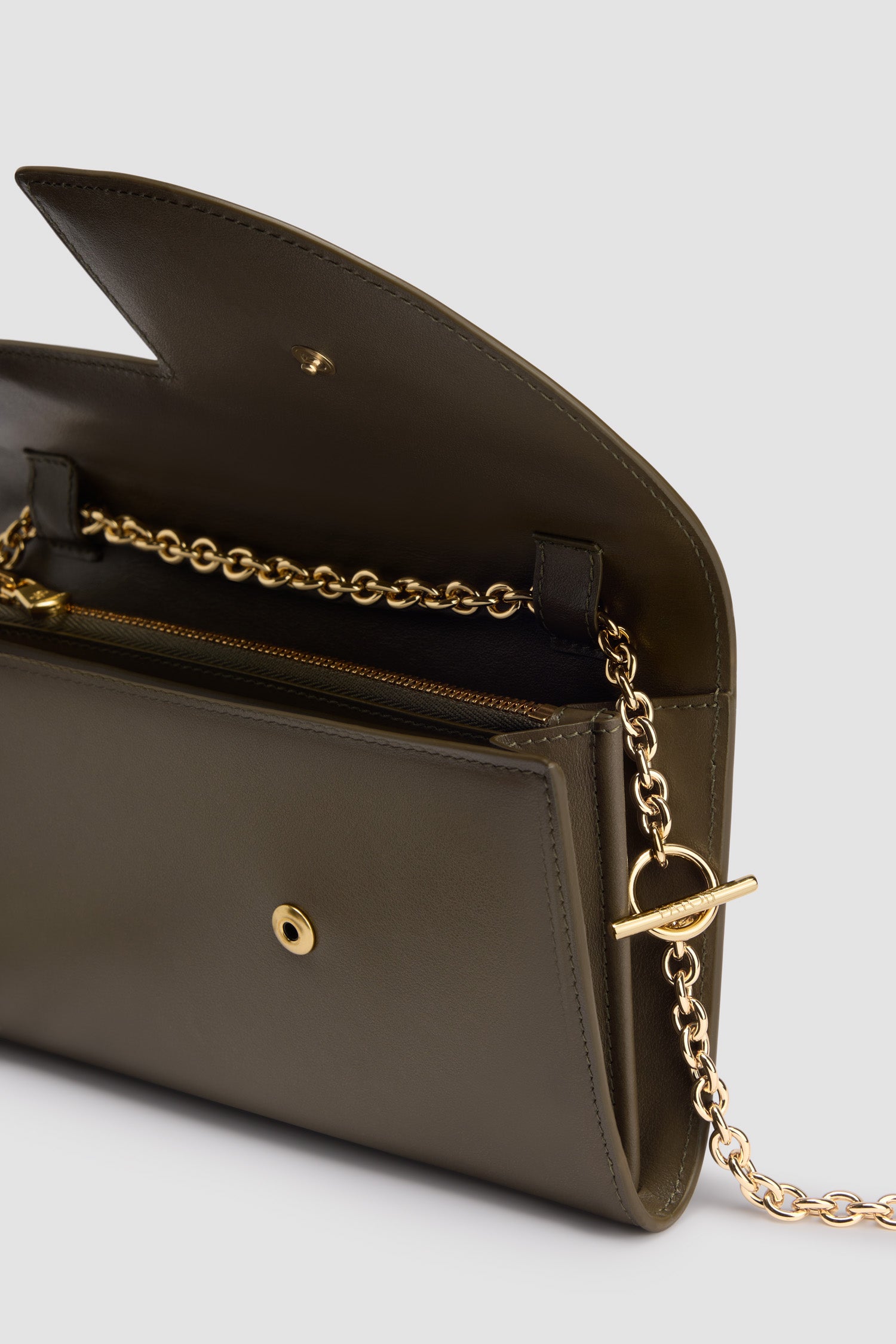 Patou - Pochette Patou à chaîne en cuir - Winter Moss - Pochette en cuir vert mousse. Réalisée en cuir de grande qualité provenant de stocks dormants issus des surplus de production. Édition limitée et numérotée disponible en 20 exemplaires. Forme compacte. Bandoulière chaîne dorée. Découpe sur le devant. Fermeture à pression. Poche zippée.
