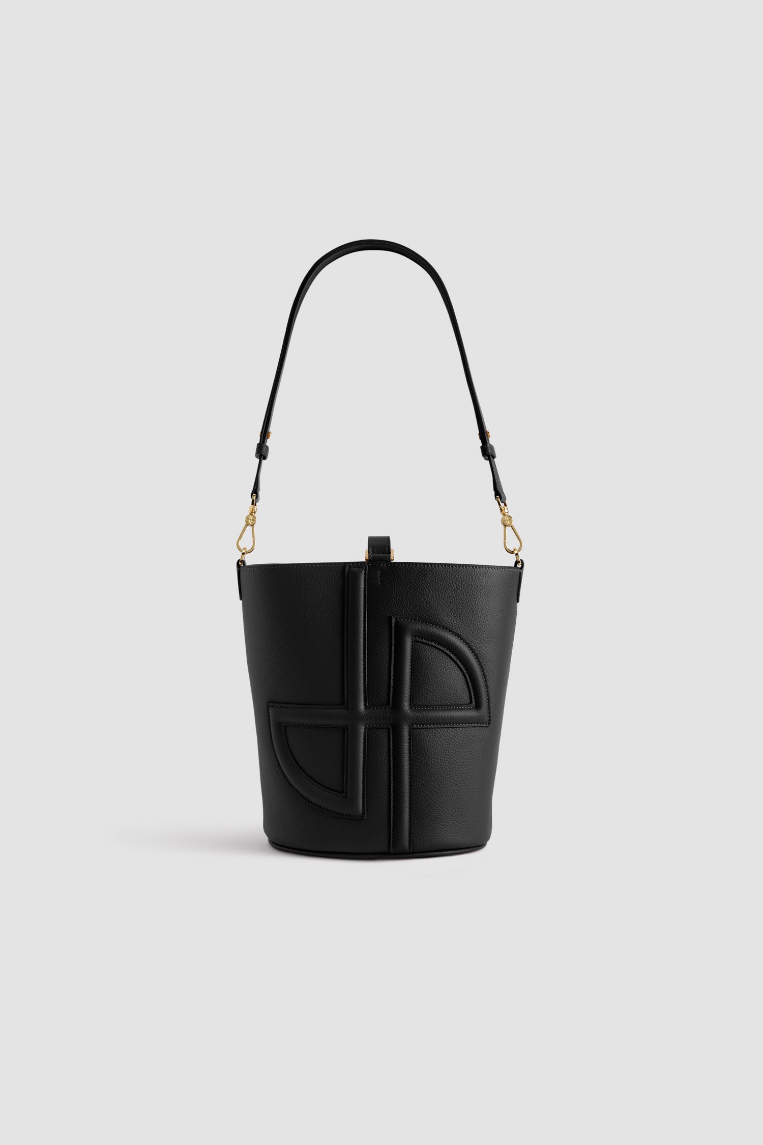 Patou - Medium JP bucket bag in leather - Black - Black grained leather handbag. Medium size. Bucket shape with a foam-padded 3D JP monogram at the front. Tab fastening. Detachable and adjustable strap. Gold-tone hardware. Metal feet.