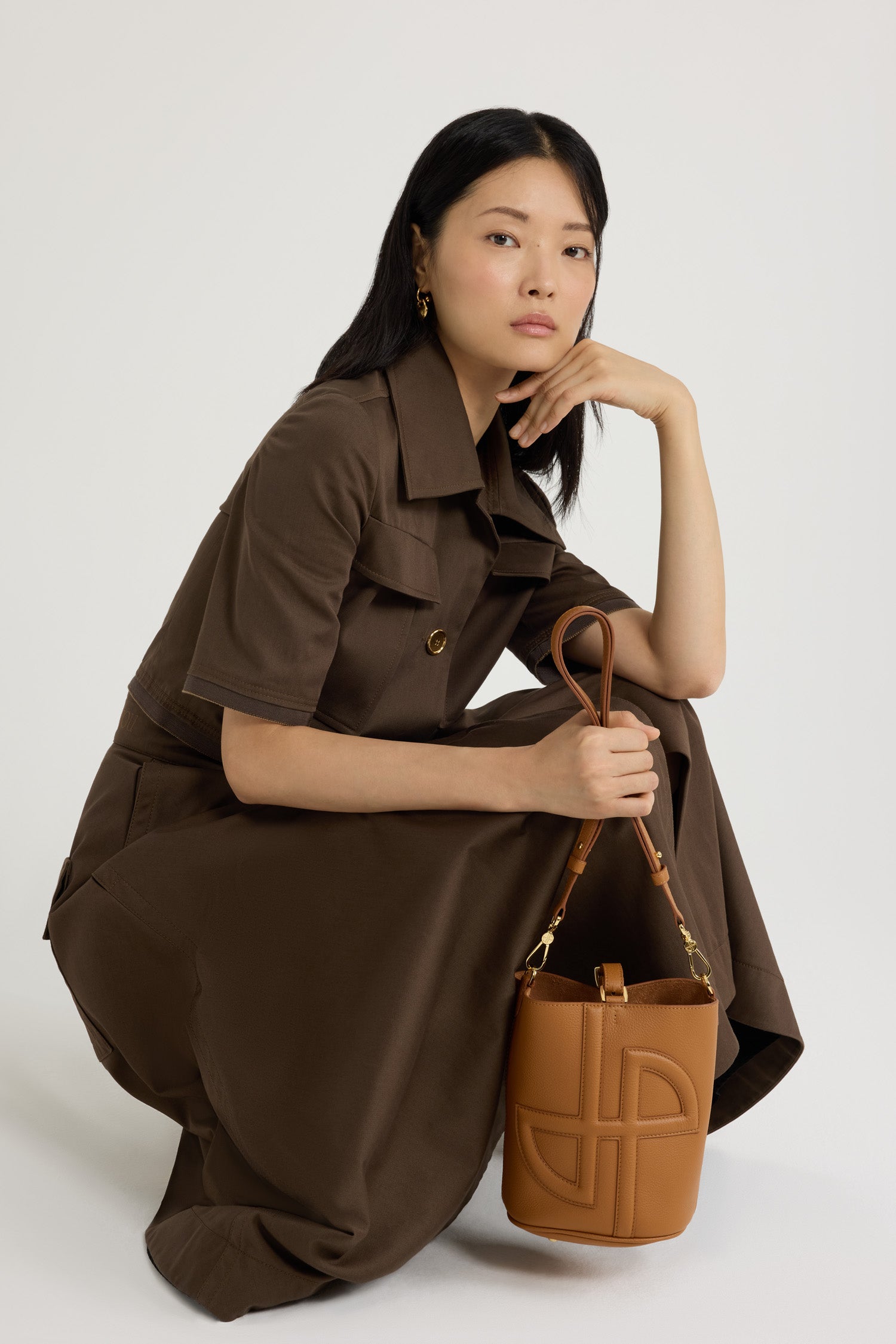 Patou - レザー&キャンバス JP バケットバッグ スモール - Caramel - キャラメルのグレインレザー製ハンドバッグ。小さめのサイズ。バケット型。フロントにフォームパッド入りの3D JPモノグラム。スタッズ付きタブ留め。取り外し・調節可能なストラップ。ゴールドトーンのメタルパーツ。金属製の底鋲。