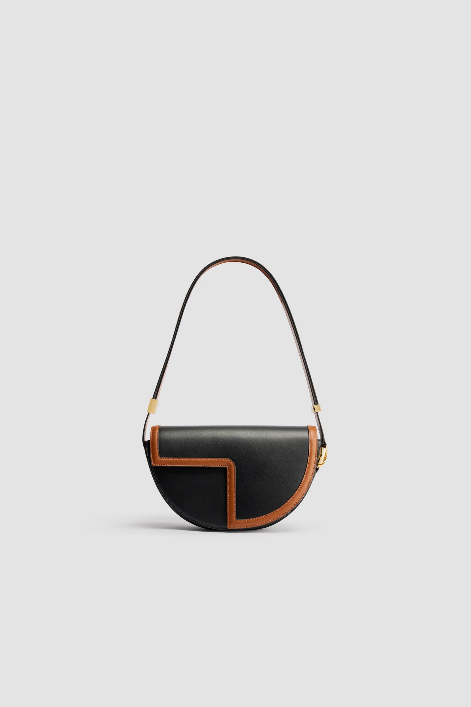 Patou - Zweifarbige Tasche Le Patou aus Leder - Black Chestnut - Lederhandtasche in Schwarz und Kastanienbraun. Gefertigt aus einzigartigen Materialien, die aus unverwendeten hochwertigen Lederhäuten gewonnen wurden. 40 nummerierte Exemplare in limitierter Auflage. Halbkreis-Format mit geometrischen, vom JP-Monogramm inspirierten Cut-Outs. Goldfarbene Metallelemente mit JP-Monogramm-Detail an der Seite. Verstellbarer Riemen zum Tragen über der Schulter, diagonal am Körper oder in der Hand. Magnetverschluss mit goldfarbenem JP-Detail. Mehrere Fächer auf der Innenseite. Öko-Futter.Maße: 25 cm (Länge), 15 cm (Höhe), 6 cm (Tiefe)3 Längen für den verstellbaren Riemen: 47 cm (zum Tragen über der Schulter), 36 cm (zum Tragen diagonal am Körper), 28 cm (zum Tragen in der Hand)