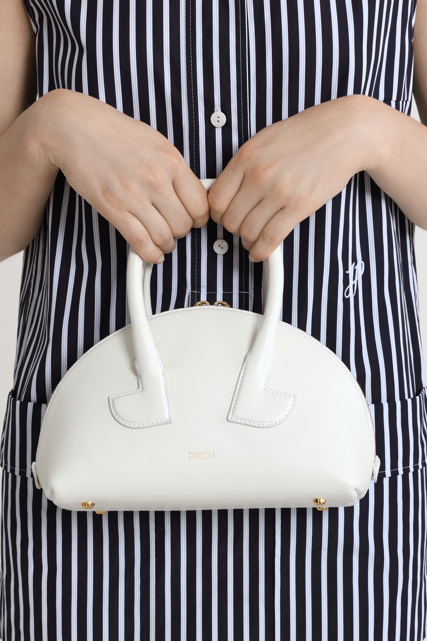 Patou - Le Patou Bowlingtasche aus Leder - White - Weiße Handtasche aus Glattleder. Bowlingform. Zwei Henkel mit geometrischen Ausschnitten. Abnehmbarer Schulterriemen. Goldfarbener Zwei-Wege-Reißverschluss. Goldfarbenes, eingeprägtes Patou Logo vorne. Füße aus goldfarbenem Metall.