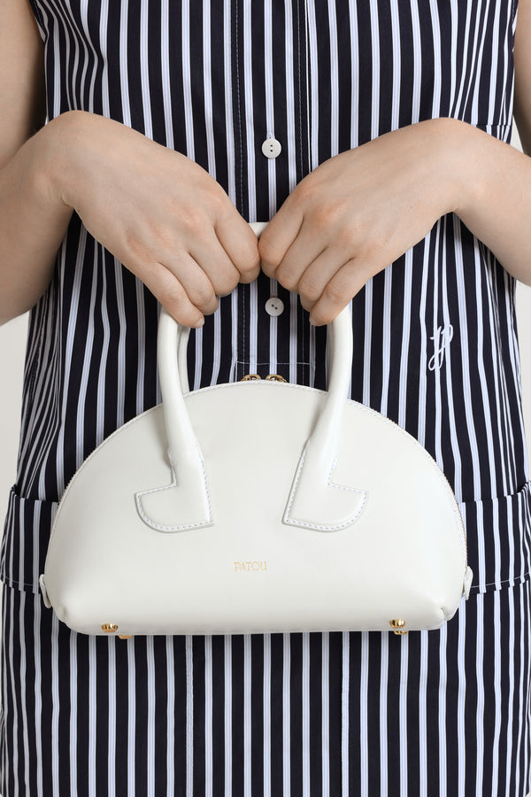 Patou - Borsa Le Patou Bowling in pelle - White - Borsa in pelle liscia bianca. Forma bowling. Doppio manico con dettagli geometrici. Tracolla rimovibile. Chiusura con zip oro a doppio cursore. Logo Patou oro sul davanti. Piedini in metallo oro.