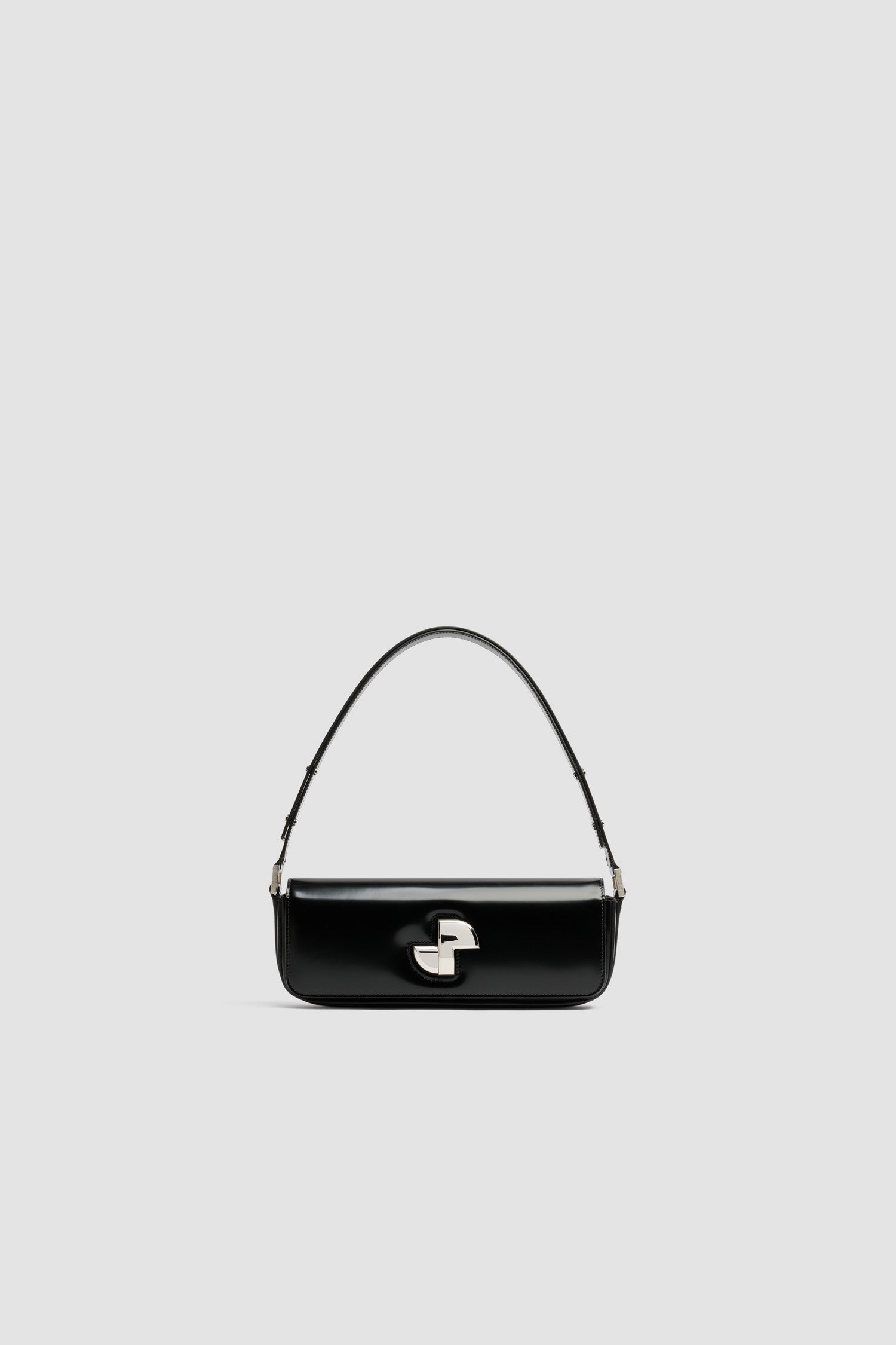 Patou - Le Lock Baguette en cuir - Black - Sac en cuir brillant noir. Sac de jour classique revisité. Forme allongée. Fermoir rotatif JP argenté d'inspiration Art Déco sur le devant. Bandoulière réglable pouvant être portée courte ou longue. Doublure en cuir.