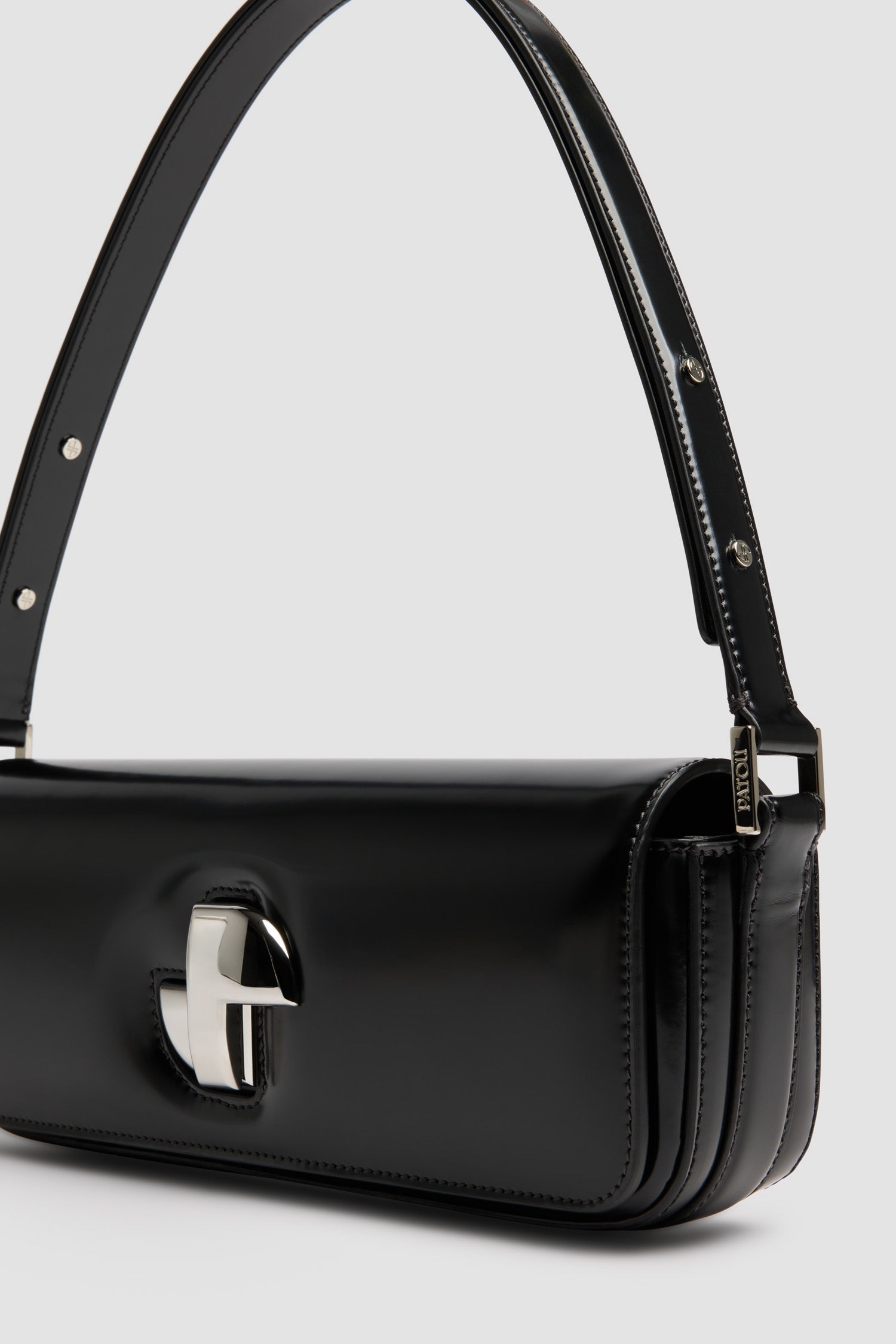 Patou - Le Lock Baguette en cuir - Black - Sac en cuir brillant noir. Sac de jour classique revisité. Forme allongée. Fermoir rotatif JP argenté d'inspiration Art Déco sur le devant. Bandoulière réglable pouvant être portée courte ou longue. Doublure en cuir.