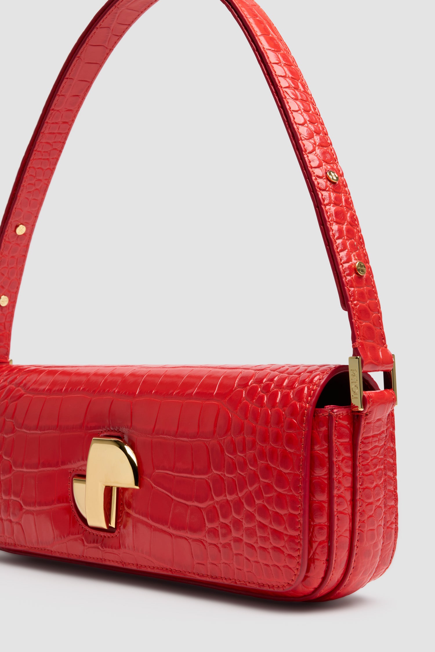 Patou - Le Lock Baguette bag in crocodile-embossed leather - Babylone Red - Babylone Red crocodile-embossed leather handbag. Classic day bag inspiration with an elongated shape. Gold Art Deco JP twist clasp at the front. Adjustable strap that allows it to be worn short or long. Leather lining.