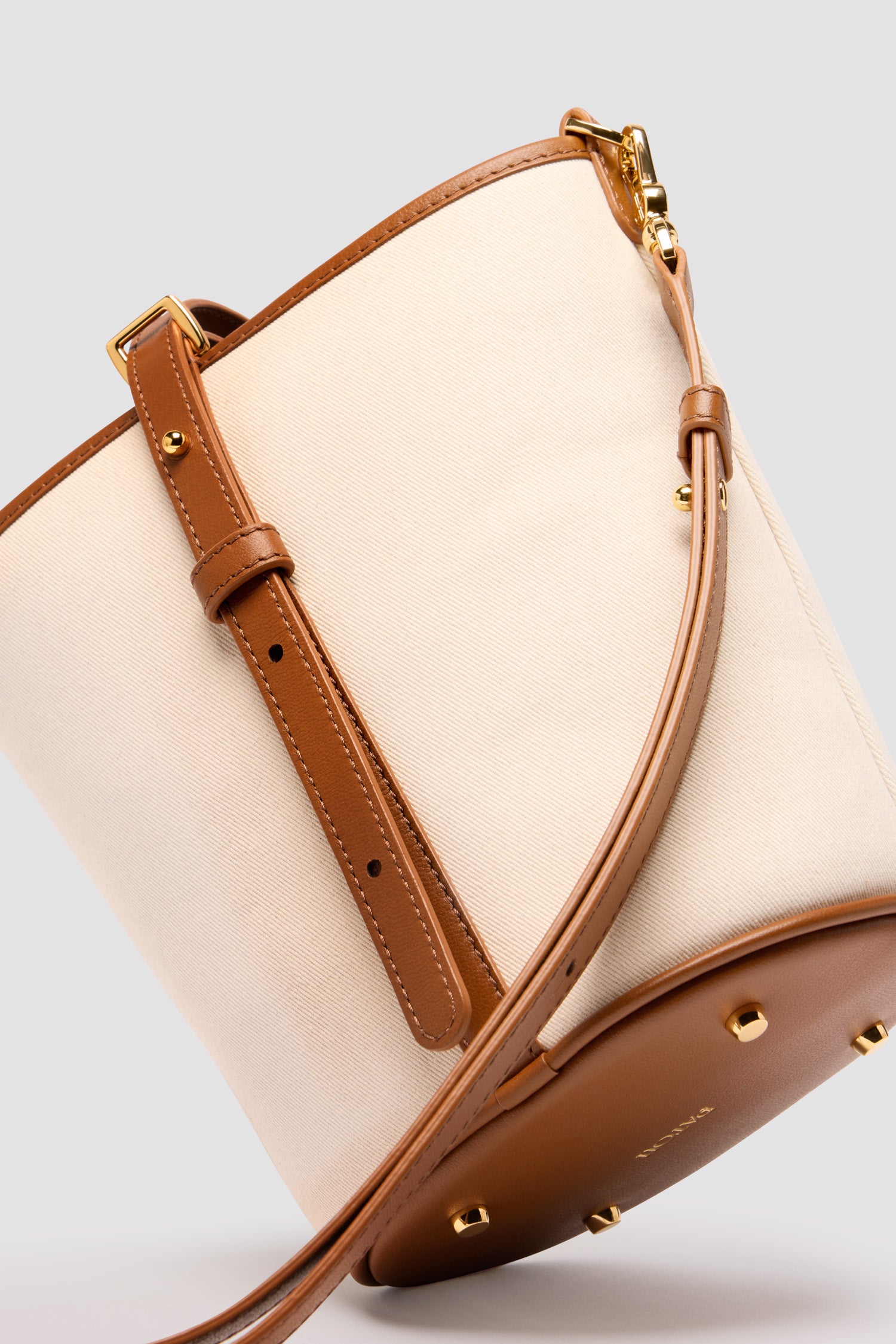 Patou - Small JP bucket bag in leather and canvas - Caramel - Caramel leather and natural canvas handbag. Crafted using unique materials sourced from unused high-quality leather hides. Small size. Bucket shape with a foam-padded 3D JP monogram at the front. Tab fastening with stud closure. Detachable and adjustable strap. Gold-tone hardware. Metal feet. Gold-embossed Patou logo on the base.