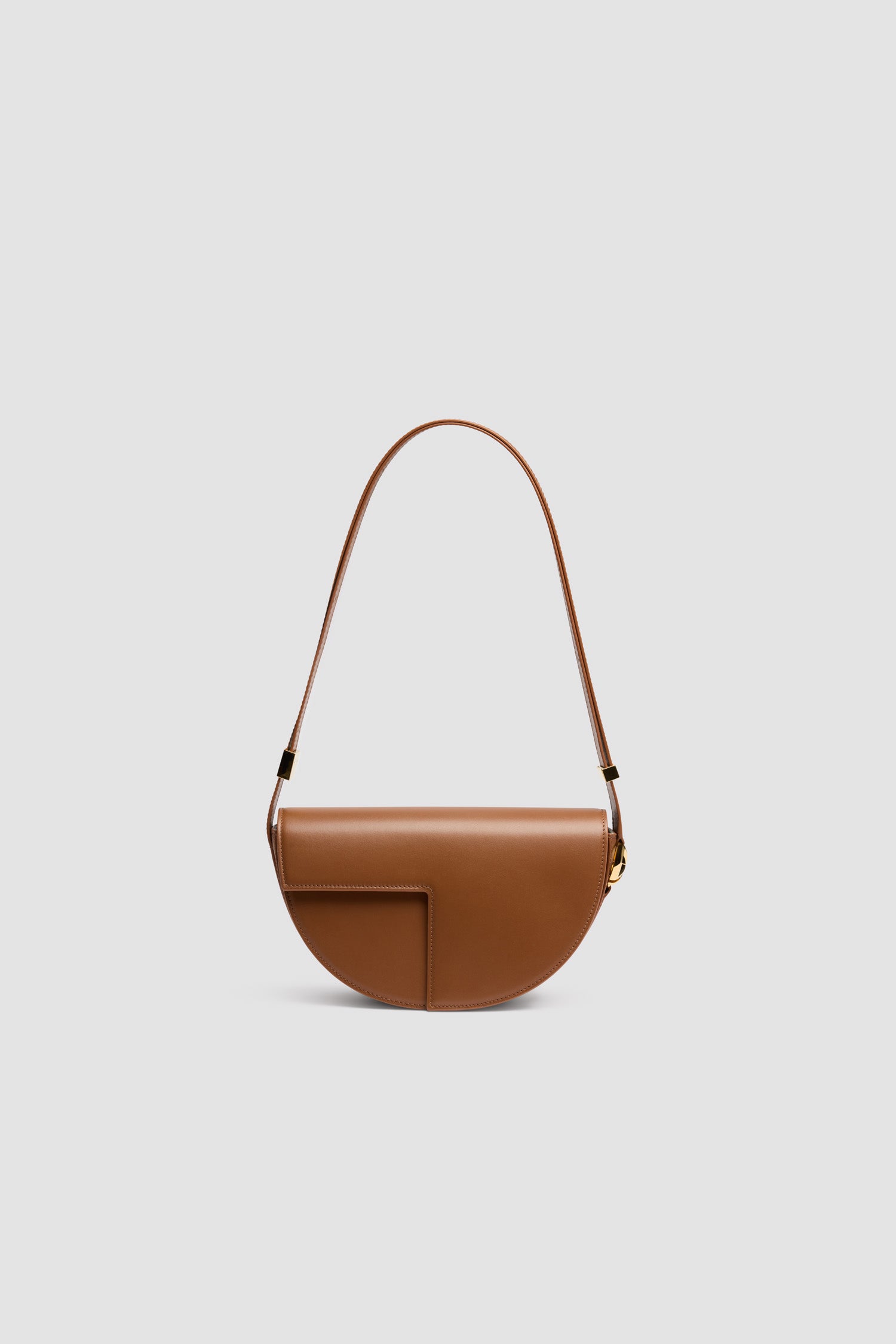 Patou - Le Patou bag in leather - Mahogany - Mahogany smooth leather handbag. Half-circle shape with geometric cut-outs inspired by the JP monogram. Gold-tone hardware with JP monogram detail at the side. Adjustable strap that allows it to be worn on the shoulder, across the body or carried by hand. Magnetic closure with gold-tone JP detail. Multiple compartments inside.Measures: 25 cm (length), 15 cm (height), 6 cm (depth)3 lengths for the adjustable strap: 47 cm (on the shoulder), 36 cm (across the body), 28 cm (carried by hand)