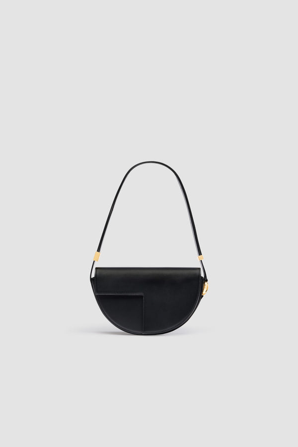Patou - Le Patou bag in leather - Black - Black smooth leather handbag. Half-circle shape with geometric cut-outs inspired by the JP monogram. Gold-tone hardware with JP monogram detail at the side. Adjustable strap that allows it to be worn on the shoulder, across the body or carried by hand. Magnetic closure with gold-tone JP detail. Multiple compartments inside.Measures: 25 cm (length), 15 cm (height), 6 cm (depth)3 lengths for the adjustable strap: 47 cm (on the shoulder), 36 cm (across the body), 28 cm (carried by hand)
