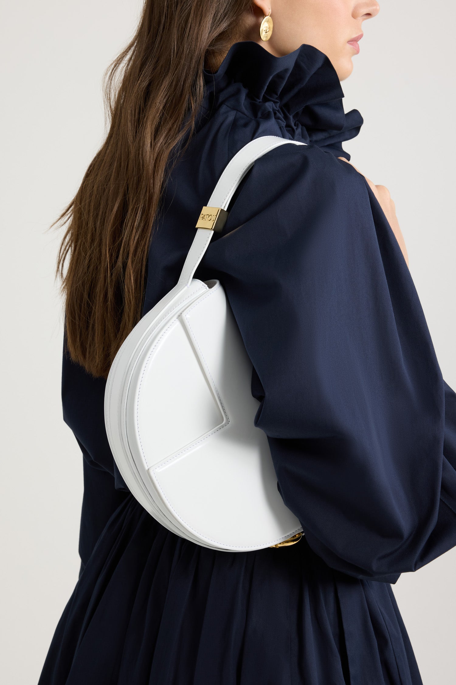 Patou - レザー製 Le Patou バッグ - White - ホワイトのつややかなレザー製ハンドバッグ。JPモノグラムにインスピレーションを得た幾何学的なカットアウトをあしらった半円形のフォルム。サイドにゴールドトーンのメタルパーツとJPモノグラム ディテール。調整可能なストラップで、ショルダーバッグ、クロスボディバッグ、ハンドバッグとしてお使いいただけます。ゴールドトーンのJPディテールをあしらったマグネットクロージャー。内部に複数のコンパートメント。長さ: 長さ: 25cm、高さ: 15cm、幅: 6cm ストラップの長さは3段階で調節可能:47 cm (ショルダー)、36 cm (クロスボディ)、28 cm (ハンド)