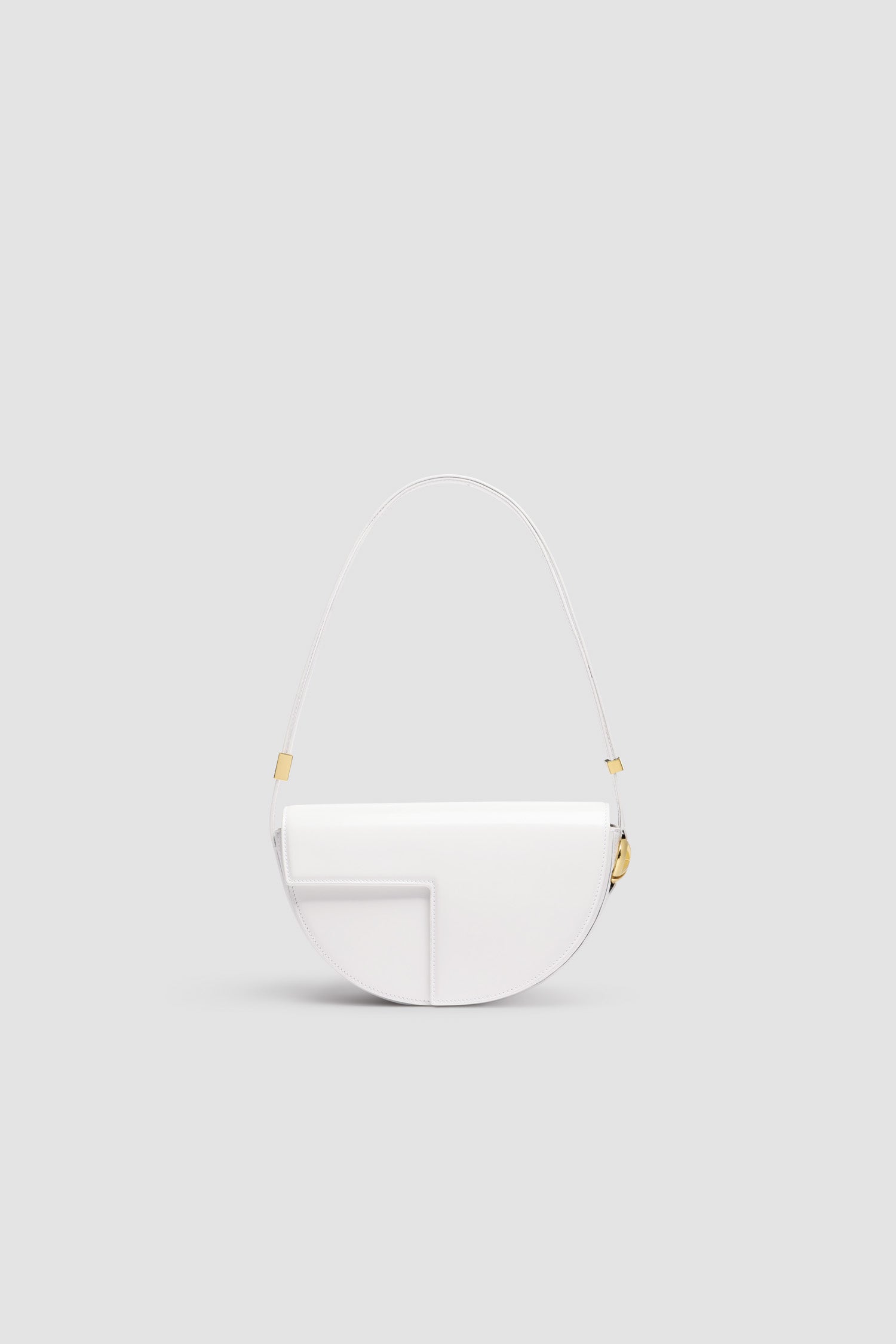Patou - レザー製 Le Patou バッグ - White - ホワイトのつややかなレザー製ハンドバッグ。JPモノグラムにインスピレーションを得た幾何学的なカットアウトをあしらった半円形のフォルム。サイドにゴールドトーンのメタルパーツとJPモノグラム ディテール。調整可能なストラップで、ショルダーバッグ、クロスボディバッグ、ハンドバッグとしてお使いいただけます。ゴールドトーンのJPディテールをあしらったマグネットクロージャー。内部に複数のコンパートメント。長さ: 長さ: 25cm、高さ: 15cm、幅: 6cm ストラップの長さは3段階で調節可能:47 cm (ショルダー)、36 cm (クロスボディ)、28 cm (ハンド)