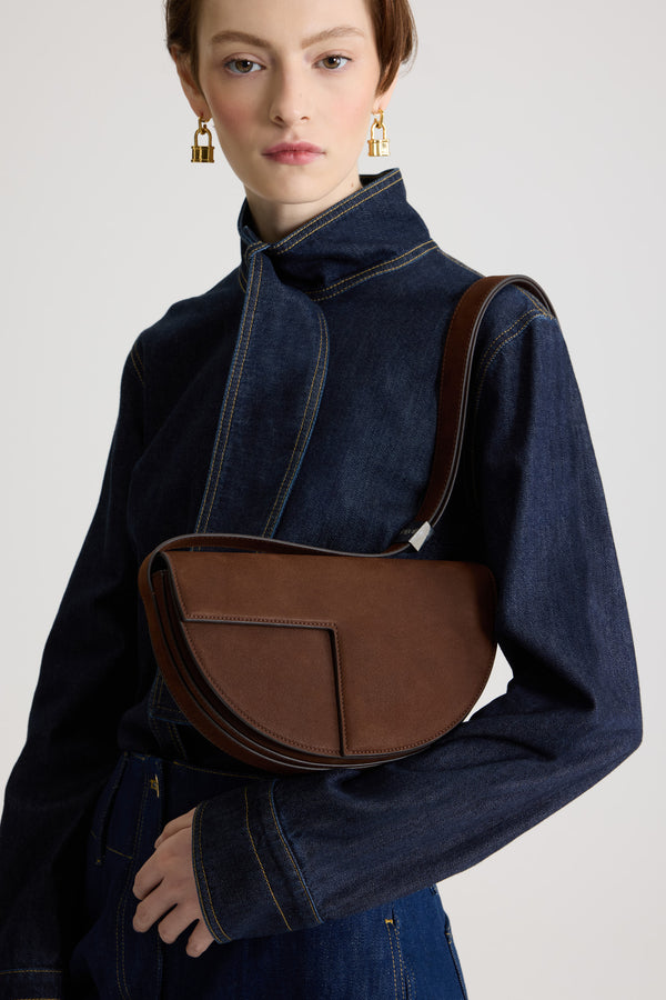 Patou - Sac Le Patou en nubuck - Smoked Ebony - Sac à main en nubuck couleur ébène fumé. Forme demi-lune avec découpes géométriques inspirée du monogramme JP. Pièce en métal doré avec détail JP sur le côté. Bandoulière ajustable permettant un porté épaule, en bandoulière ou à la main. Fermeture aimantée avec détail JP doré. Compartiments multiples à l’intérieur.Dimensions : 25 cm de longueur, 15 cm de hauteur et 6 cm de profondeurBandoulière ajustable en 3 longueurs : 47 cm (porté épaule), 36 cm (porté en bandoulière), 28 cm (porté à la main)