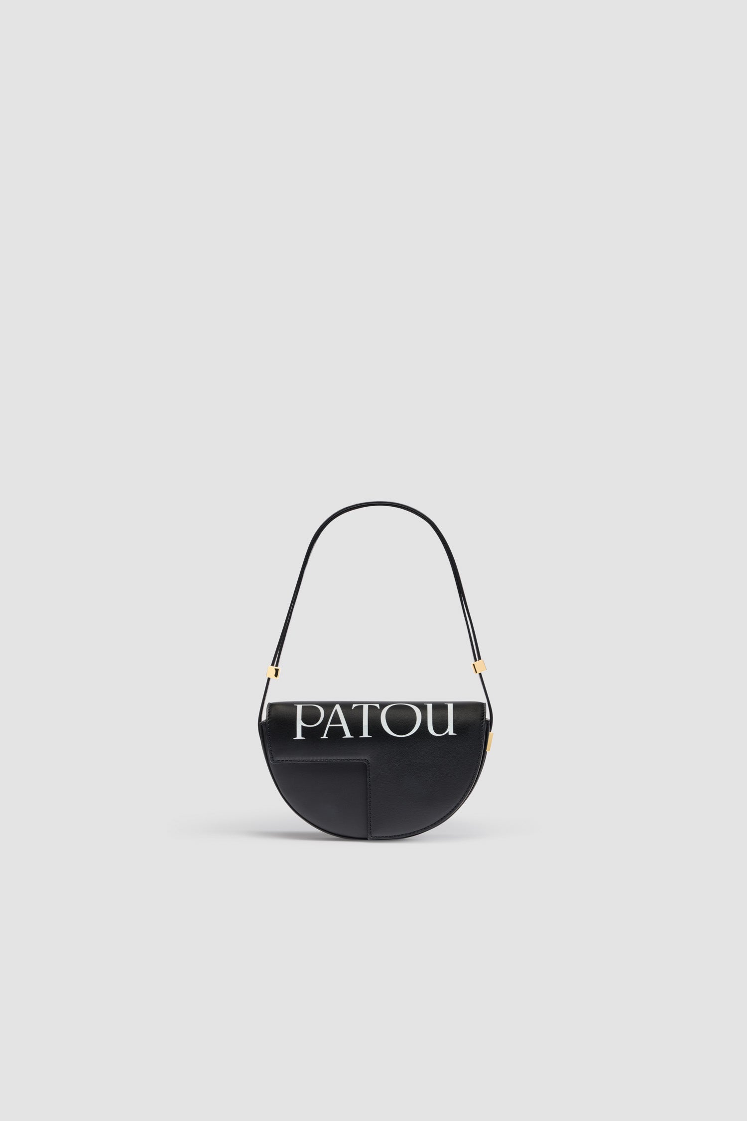 Patou - レザー製 Le Petit Patou ロゴバッグ - Black and White - ブラックのレザー製ハンドバッグ。JPモノグラムにインスピレーションを得た幾何学的なカットアウトをあしらった半円形のフォルム。サイドにゴールドトーンのメタルパーツとパトゥ刻印入りディテール。調整可能なストラップで、ショルダーバッグ、クロスボディバッグ、ハンドバッグとしてお使いいただけます。ゴールドトーンのJPディテールをあしらったマグネットクロージャー。内側のコンパートメント。エコライニング。サイズ: 横:20 cm 高さ:13 cm 幅:5 cm