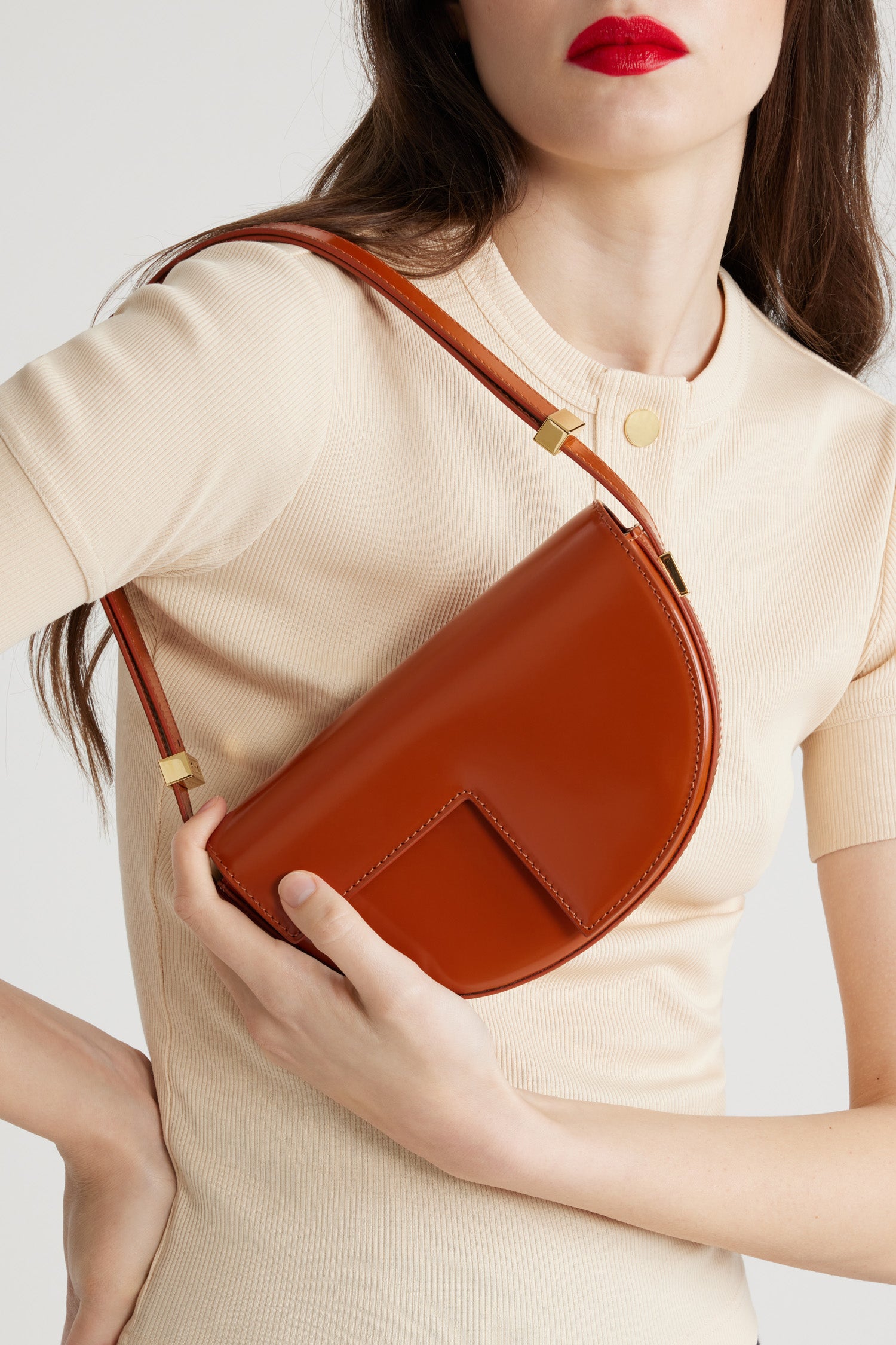 Patou - Le Petit Patou - Autumn Leaf - Sac en cuir marron feuille d'automne. Forme demi-lune avec découpes géométriques inspirée du monogramme JP. Pièce métallique gravée Patou sur le côté. Bandoulière ajustable permettant un porté épaule, en bandoulière ou à la main. Fermeture aimantée avec détail JP doré. Doublure éco-friendly.Dimensions : 20 cm de longueur, 13 cm de hauteur et 5 cm de profondeur.