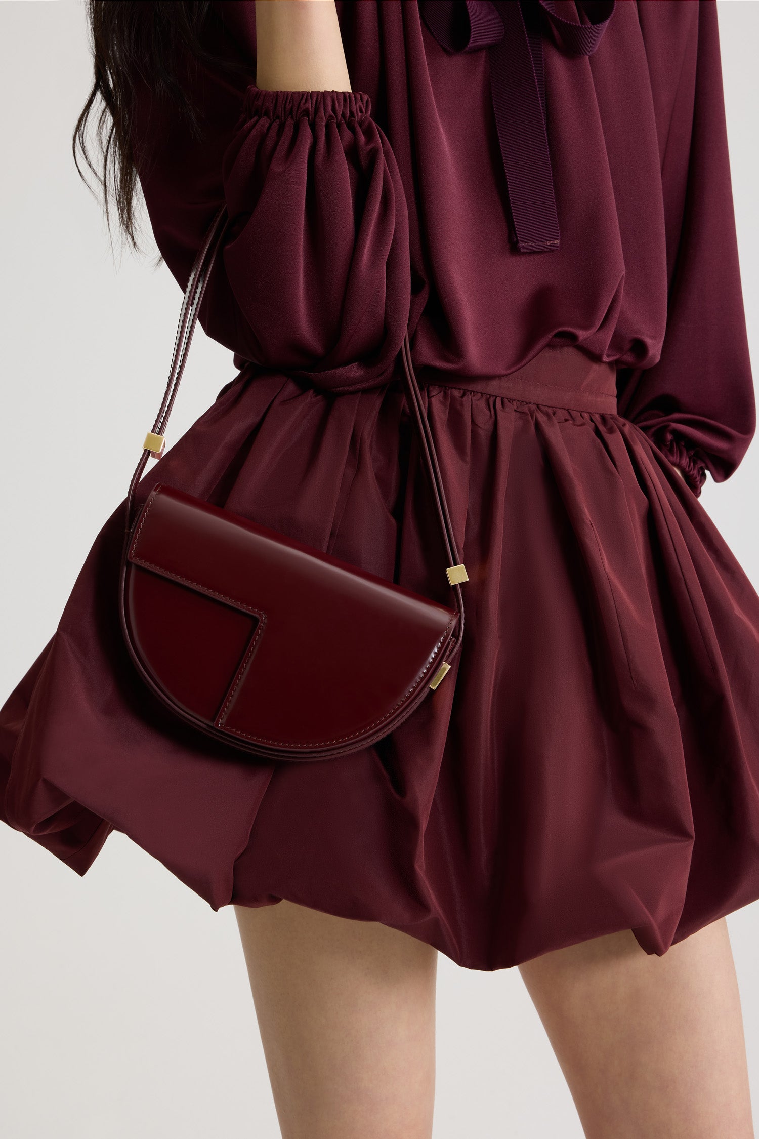 Patou - Borsa Le Petit Patou in pelle - Syrah - Borsa in pelle lucida borgogna Syrah. Forma a mezzaluna con tagli geometrici ispirati al monogramma JP. Pezzi in metallo oro con logo Patou inciso sul lato. Tracolla regolabile che consente di portare la borsa a spalla, a bandoliera o a mano. Chiusura magnetica con dettaglio JP oro. Compartimento interno.Dimensioni: 20 cm (lunghezza), 13 cm (altezza), 5 cm (larghezza)