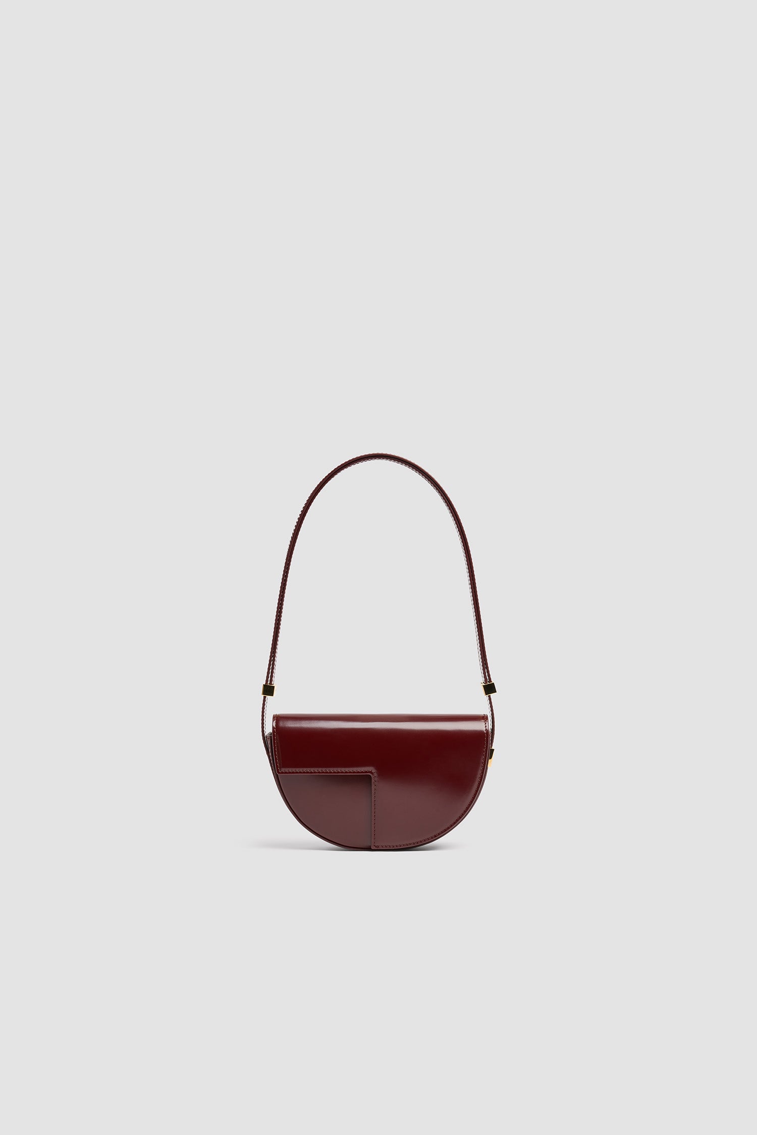 Patou - Borsa Le Petit Patou in pelle - Syrah - Borsa in pelle lucida borgogna Syrah. Forma a mezzaluna con tagli geometrici ispirati al monogramma JP. Pezzi in metallo oro con logo Patou inciso sul lato. Tracolla regolabile che consente di portare la borsa a spalla, a bandoliera o a mano. Chiusura magnetica con dettaglio JP oro. Compartimento interno.Dimensioni: 20 cm (lunghezza), 13 cm (altezza), 5 cm (larghezza)