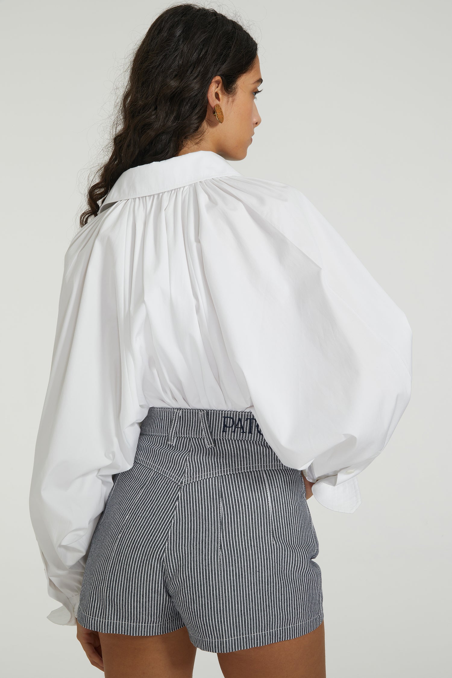 Patou - Blusa da pittore in cotone ecosostenibile - White - L'ultima opera dell'atelier Patou.Blusa in popeline di cotone ecosostenibile bianca. Vestibilità larga. Pettorina trapuntata con bottoni decentrati. Colletto classico. Arricciatura sul retro. Maniche a pipistrello. Polsini abbottonati. Orlo asimmetrico più lungo sul retro.Questo modello s'indossa oversize; ti consigliamo di ordinare la tua taglia abituale.