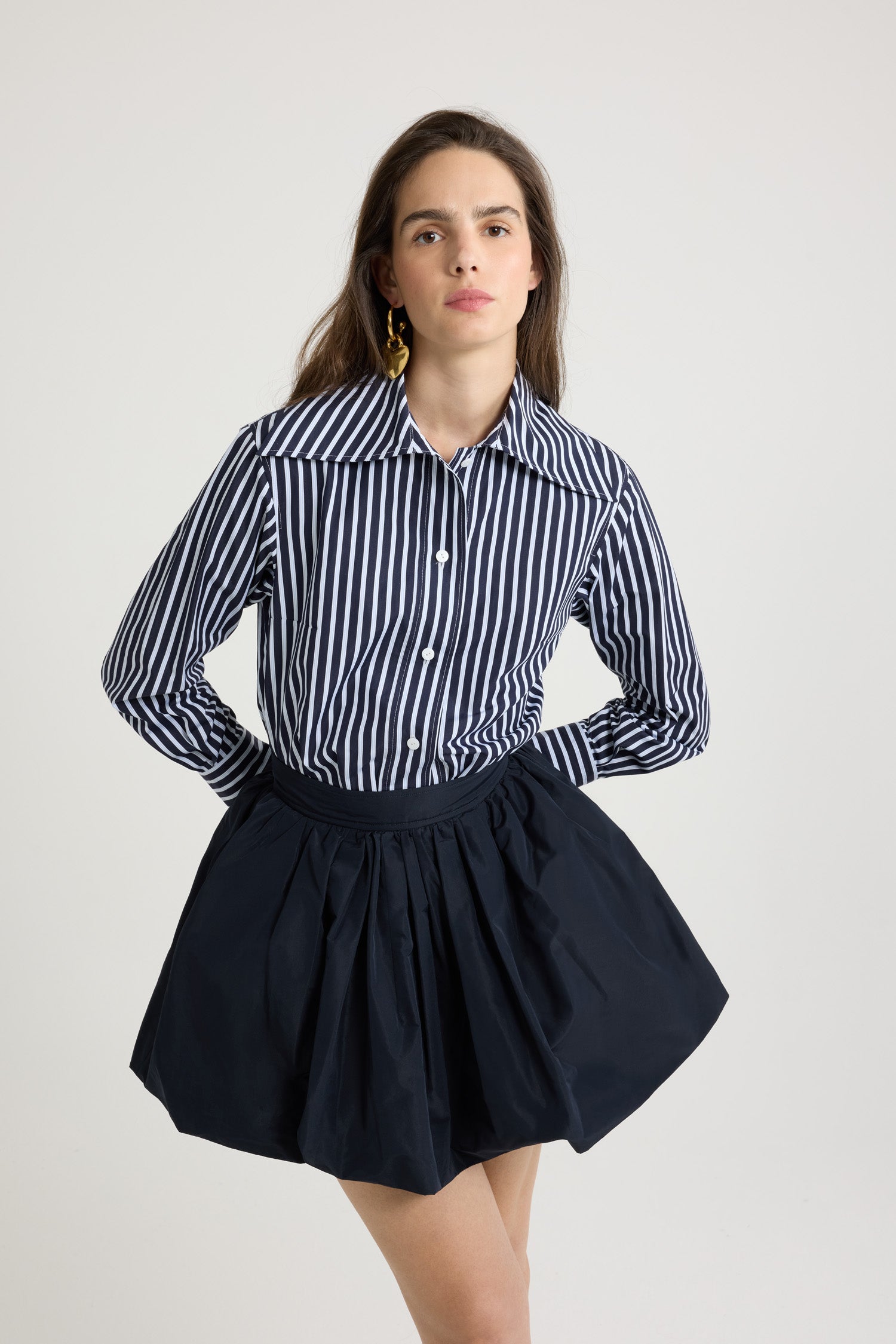 Patou - Camicia aderente in popeline di cotone bio stampato - Navy Stripes - Camicia in popeline di cotone bio blu scuro. Fantasia a righe. Silhouette a forma di violino con vestibilità aderente. Colletto largo. Chiusura con bottoni sul davanti. Polsini abbottonati. Monogramma JP ricamato sul davanti. Orlo asimmetrico più lungo sul retro.
