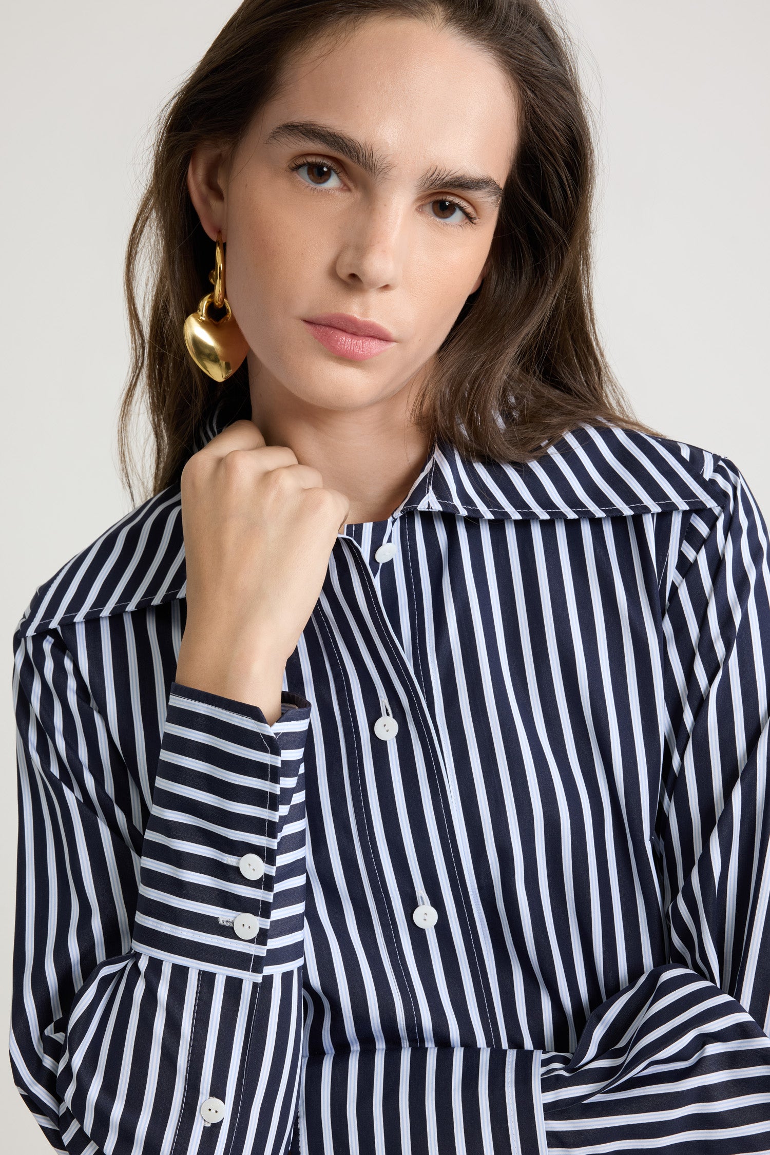 Patou - Camicia aderente in popeline di cotone bio stampato - Navy Stripes - Camicia in popeline di cotone bio blu scuro. Fantasia a righe. Silhouette a forma di violino con vestibilità aderente. Colletto largo. Chiusura con bottoni sul davanti. Polsini abbottonati. Monogramma JP ricamato sul davanti. Orlo asimmetrico più lungo sul retro.