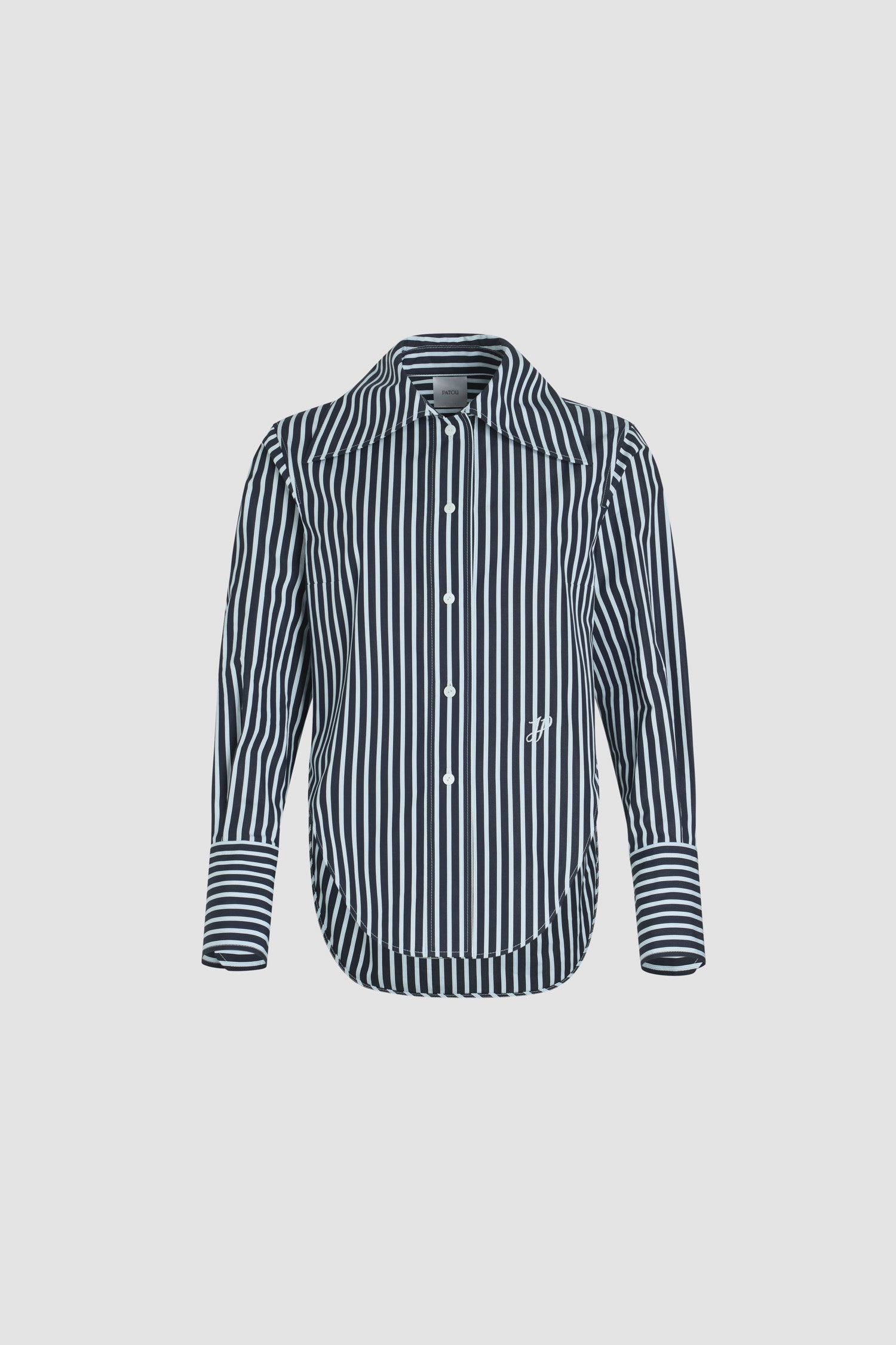 Patou - Camicia aderente in popeline di cotone bio stampato - Navy Stripes - Camicia in popeline di cotone bio blu scuro. Fantasia a righe. Silhouette a forma di violino con vestibilità aderente. Colletto largo. Chiusura con bottoni sul davanti. Polsini abbottonati. Monogramma JP ricamato sul davanti. Orlo asimmetrico più lungo sul retro.