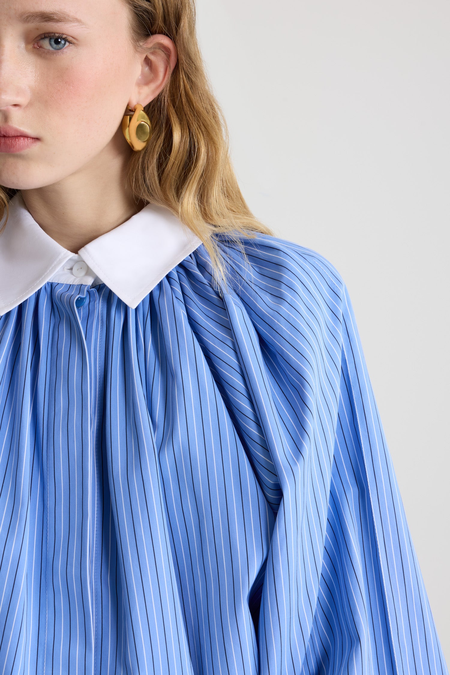 Patou - Blouse bouffante en popeline de coton bio imprimée - Ice Blue Stripes - Blouse en coton bio bleu glacier. Motif rayé. Silhouette volumineuse. Modèle légèrement court. Col classique contrastant. Fermeture par bouton dissimulé à l’avant. Manches ballon avec poignets élastiques. Ourlet bouffant.