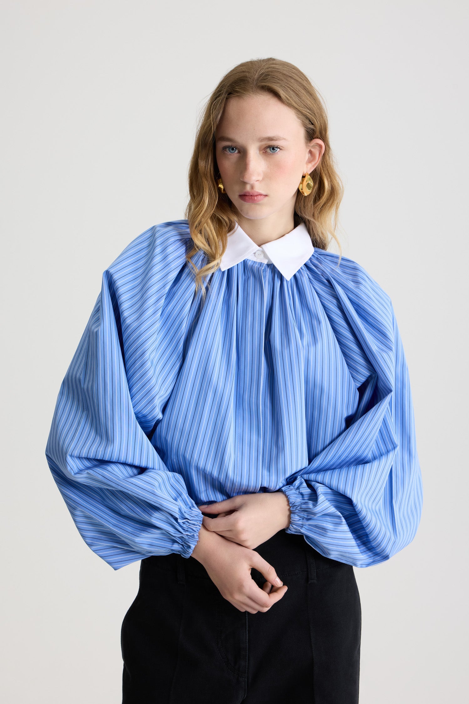 Patou - Blouse bouffante en popeline de coton bio imprimée - Ice Blue Stripes - Blouse en coton bio bleu glacier. Motif rayé. Silhouette volumineuse. Modèle légèrement court. Col classique contrastant. Fermeture par bouton dissimulé à l’avant. Manches ballon avec poignets élastiques. Ourlet bouffant.
