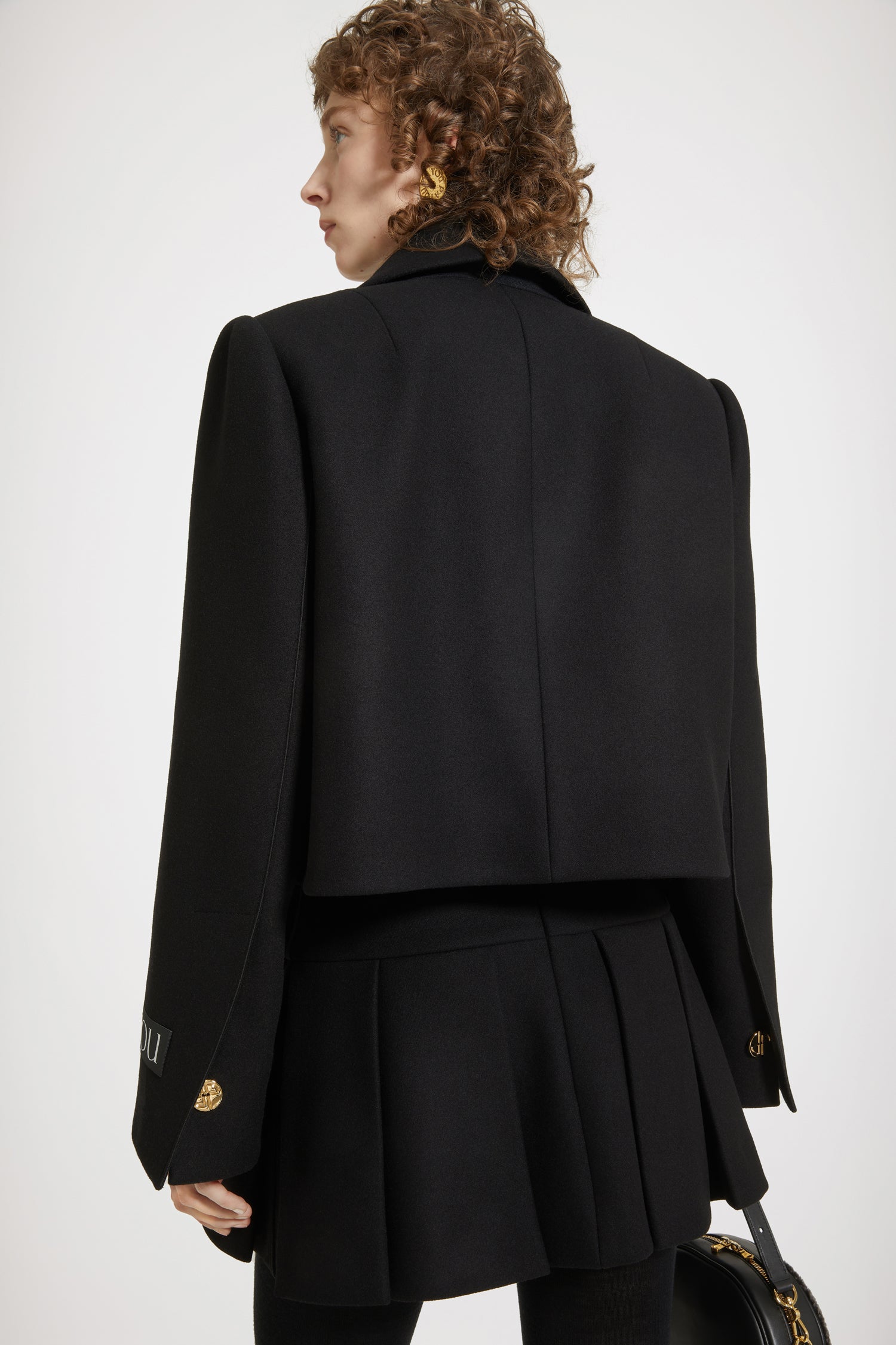 Patou - Veste courte à découpes en feutre de laine mélangée - Black - Le veste noire se découpe et se réinvente.Veste en feutre de laine mélangée noire. Coupe courte avec découpes violon sur les côtés. Larges revers. Épaulettes. Boutons dorés gravés JP d'inspiration Art Déco. Poignets à boutonnage caché. Étiquette Patou sur la manche gauche. Ganse satin à l'ourlet. Entièrement doublée.