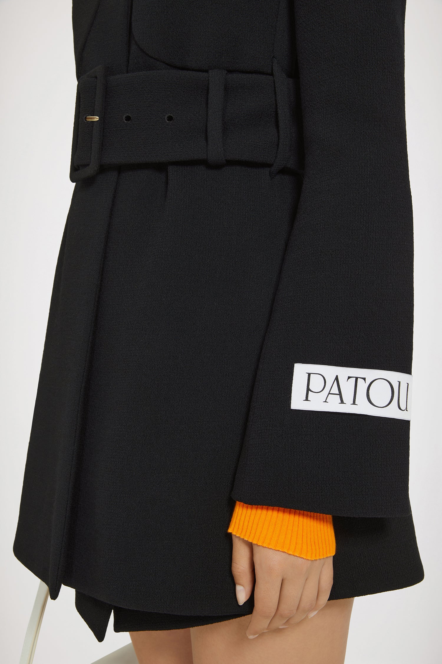 Patou - バージンウールクレープ製ベルトコート。 - Black - 遊び心をまとった感動的なテーラリング。ブラックのダブルウールクレープ製コート。ショート丈。ノッチラペル。フラップ付きのチェストポケット。ゴールドトーンのPatouエングレーブ入りボタン。ウエストに幅広の布製ベルト。袖口にボタン付き。左袖にパトゥラベル。裏地付き。
