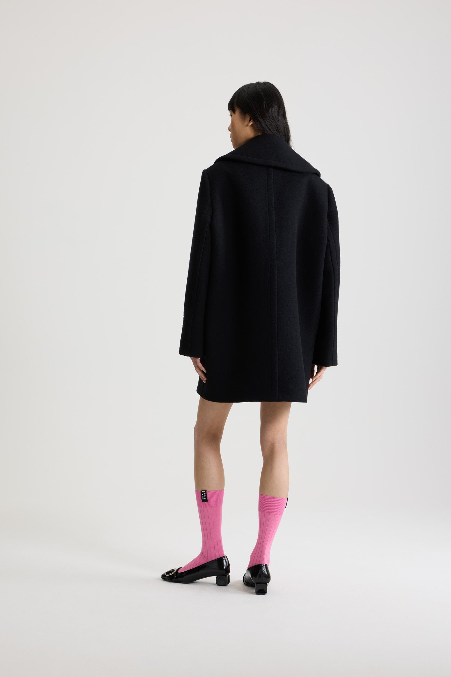 Patou - Cappotto doppiopetto in misto lana sostenibile - Black - Cappotto in misto lana sostenibile nero. Lunghezza a mezza coscia. Silhouette dritta. Costruzione doppiopetto. Ampi rever a lancia. Bottoni oro semisferici con monogramma JP. Cuciture curve sul davanti. Tasche integrate nelle cuciture. Etichetta con logo Patou sulla manica sinistra. Modello foderato.