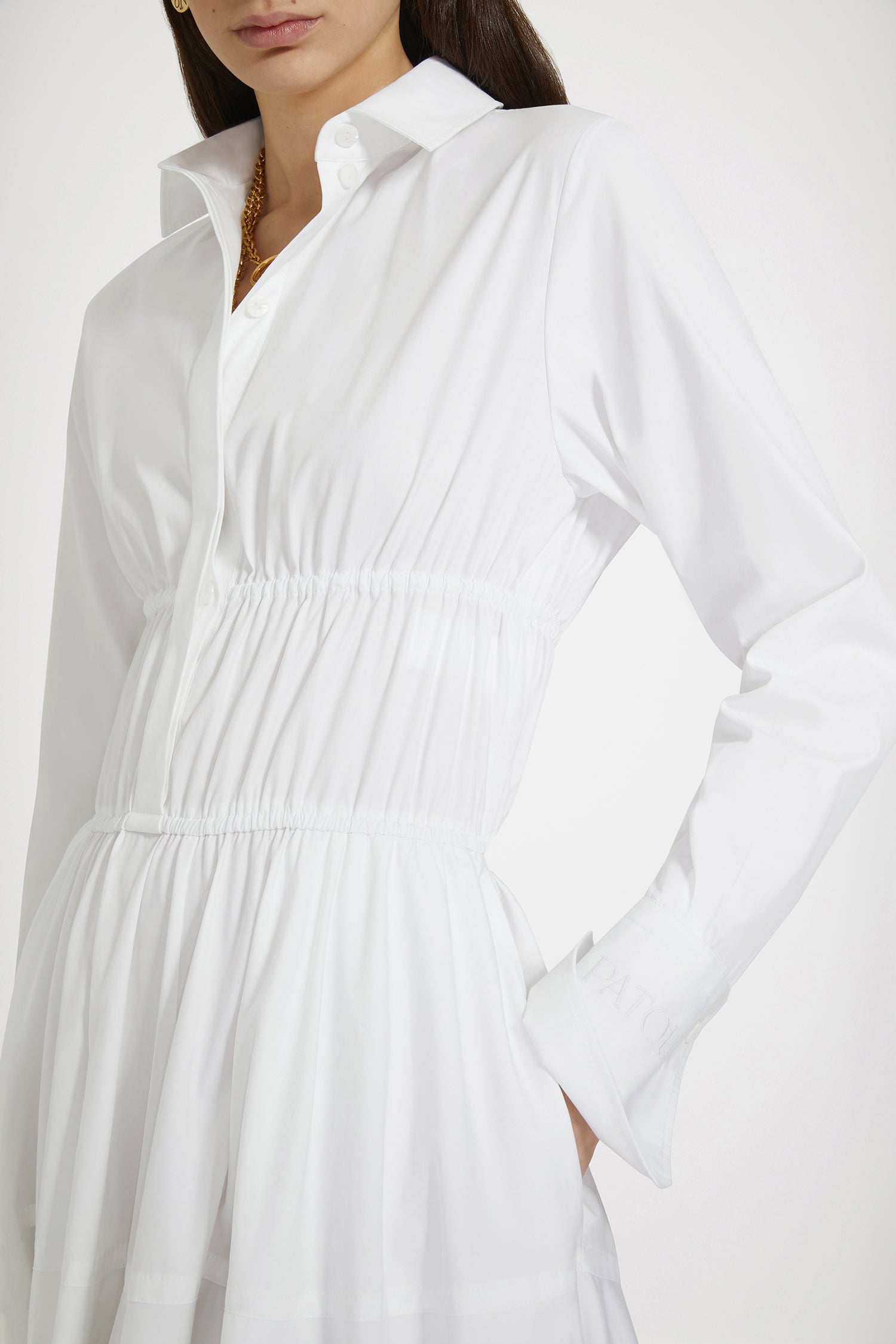 Patou - サステナブルコットン マキシ シャツドレス - White - 日々のコーデに活躍するパトゥのシャツドレスホワイトのサステナブルコットンポプリン製ドレス。マキシ丈。シャツカラー。ティアードボディス、コンシールボタン。ウエストに細い布製ベルト。袖口にボタン、左袖にPatou刺繍。ボリューム感のあるスカート。シームポケット。