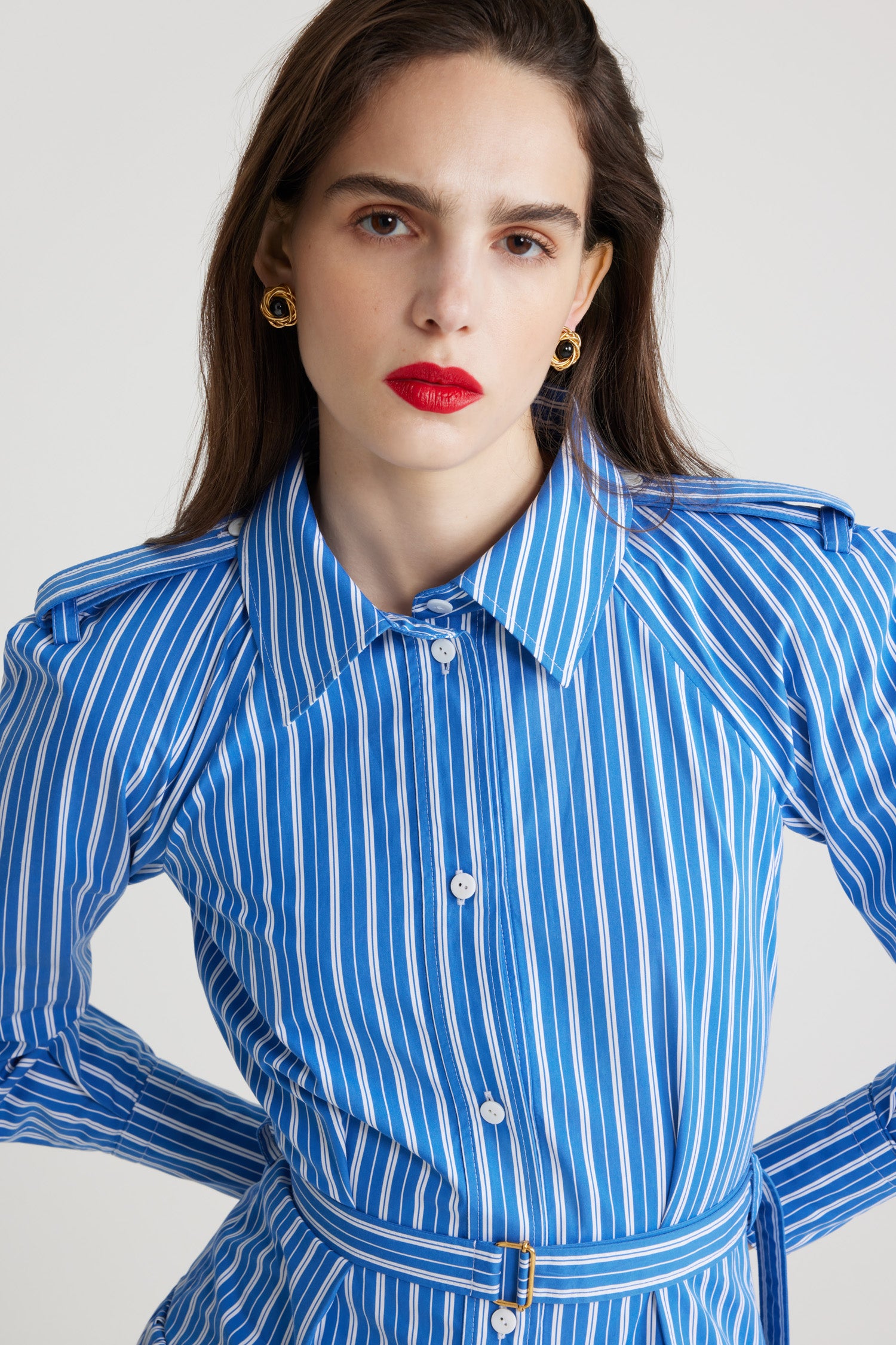 Patou - Robe chemise longue en coton imprimé éco-responsable - Victoria Blue Stripes - Robe en popeline de coton éco-responsable bleu Victoria. Motif rayures. Modèle long. Jupe volumineuse à étages. Col de chemise. Boutons en nacre gravés JP. Pattes d'épaules. Manches raglan. Poignets boutonnés. Ceinture amovible à la taille avec boucle dorée.