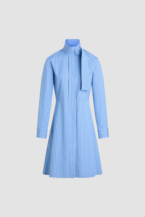 Patou - Robe chemise à col foulard en popeline de coton bio - Ice Blue Stripes - Robe en coton bio bleu glacier. Motif rayé. Longueur genou. Silhouette ajustée et évasée. Col foulard avec à l’avant. Fermeture par bouton dissimulé à l’avant. Logo Patou brodé à la taille. Poignets boutonnés. Poches latérales.