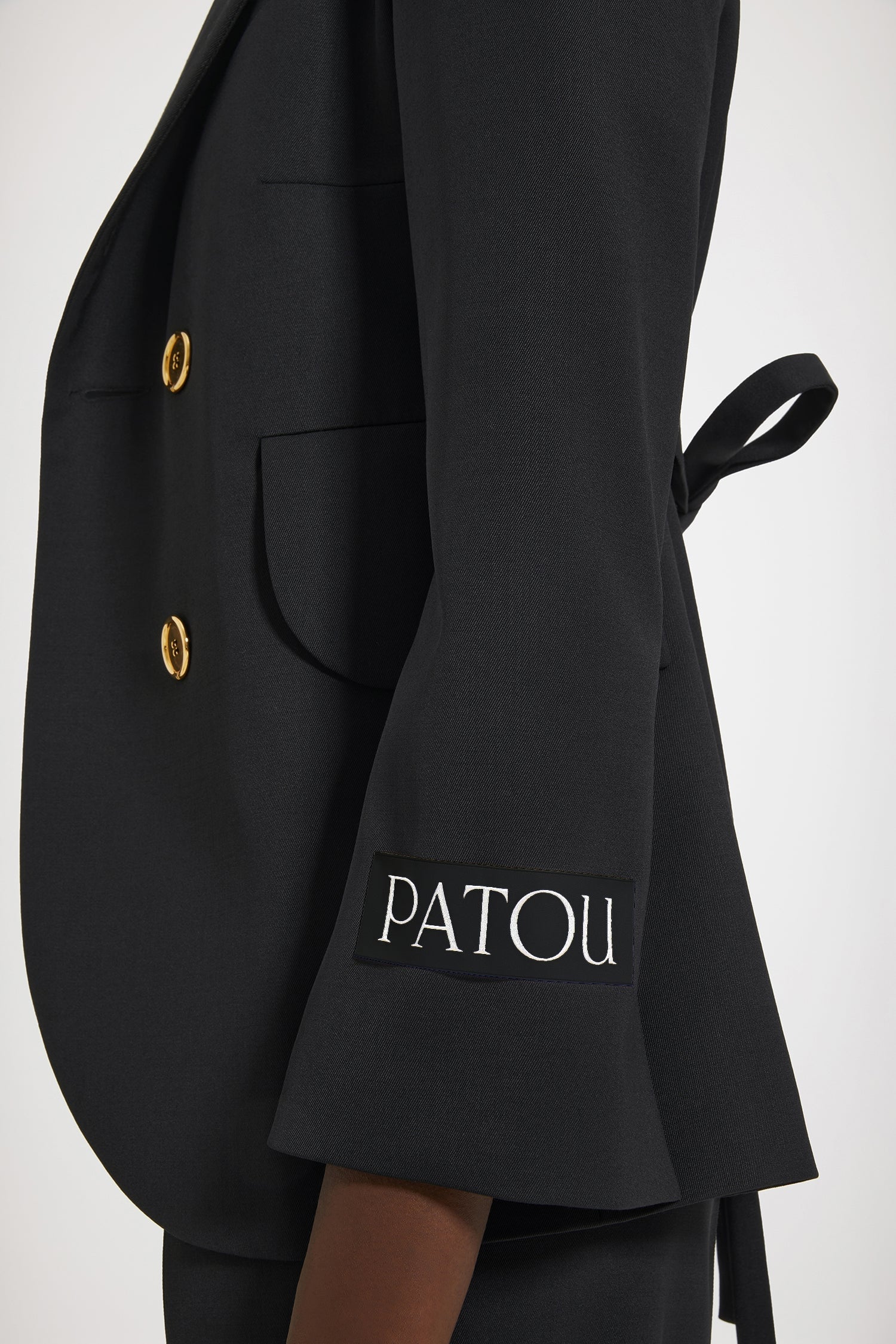 Patou - Giacca cinturata in lana tecnica - Black - Una giacca, tante possibilità.Giacca in lana tecnica nera. Modello doppiopetto. Taglio sartoriale. Rever classico largo. Bottoni oro incisi Patou. Cintura in tessuto in vita. Tasche con pattina. Maniche accorciate. Etichetta Patou sulla manica sinistra.