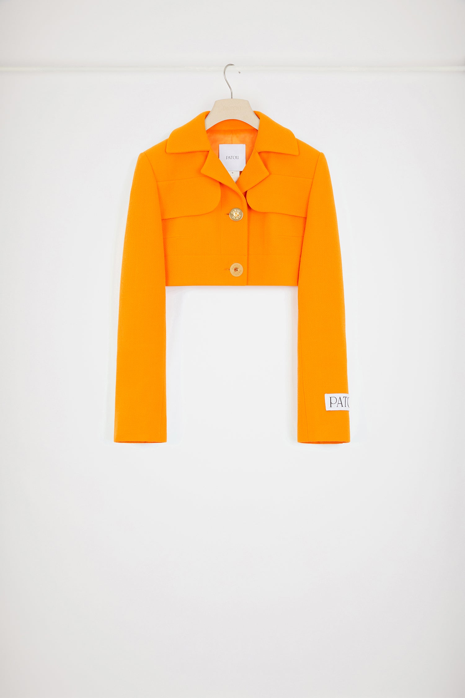 Patou - 울 크레이프 크롭 재킷 - Bright Orange - 크롭 디자인으로 단숨에 아이코닉한 매력을 선사합니다.브라이트 오렌지 컬러의 더블 울 크레이프 소재. 크롭 길이. 테일러드 실루엣. 노치 라펠. 가슴의 플랩 포켓. Patou 인그레이빙 골드 톤 버튼. 버튼 디테일의 커프스. 왼쪽 슬리브의 Patou 라벨. 안감 처리.크롭 스타일입니다.